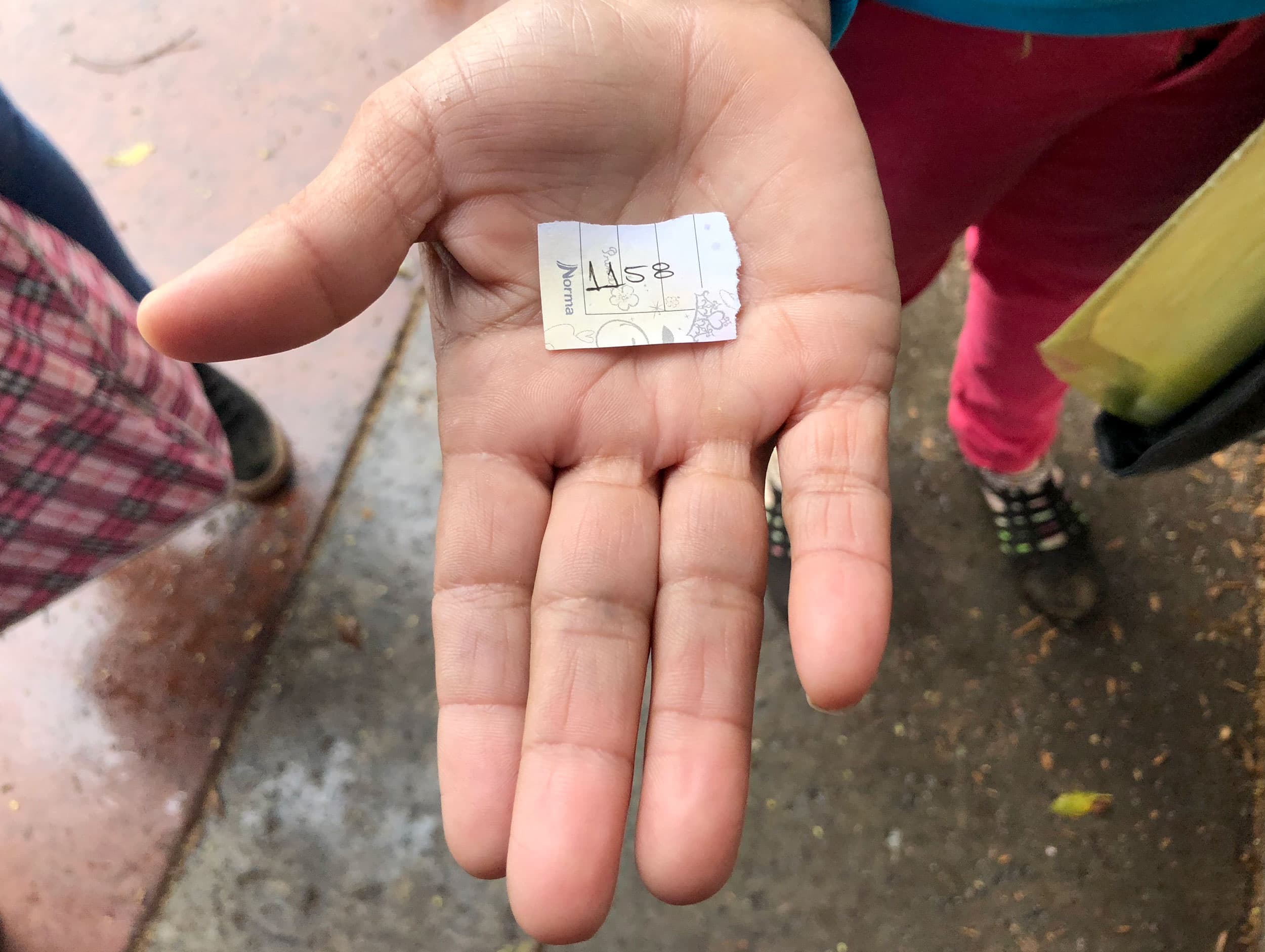 A small piece of paper with the number 1158 is in the palm on someone's hand