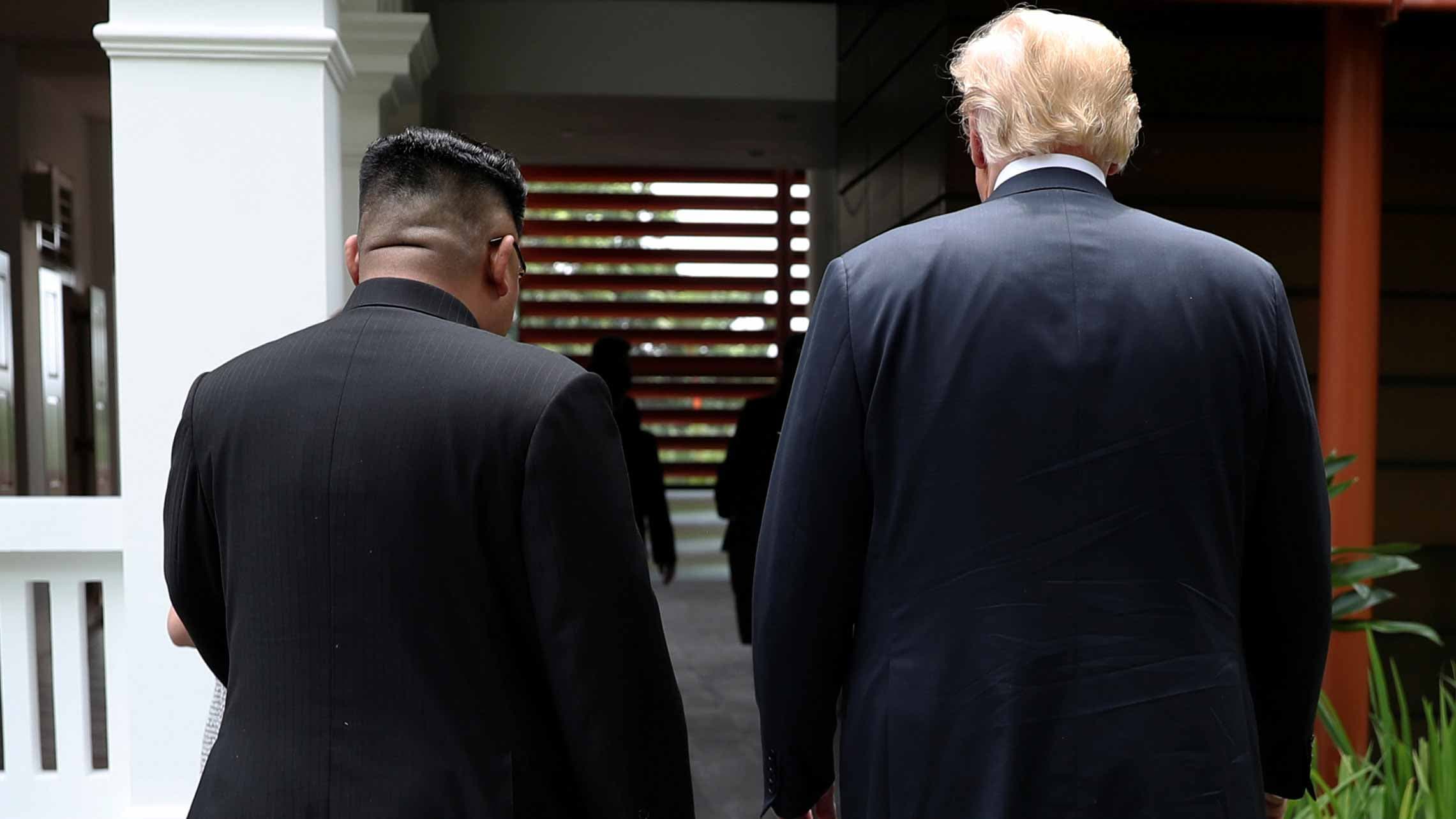 Kim Jong-un and US President Donald Trump walk side by side with their backs to the camera during their first summit.