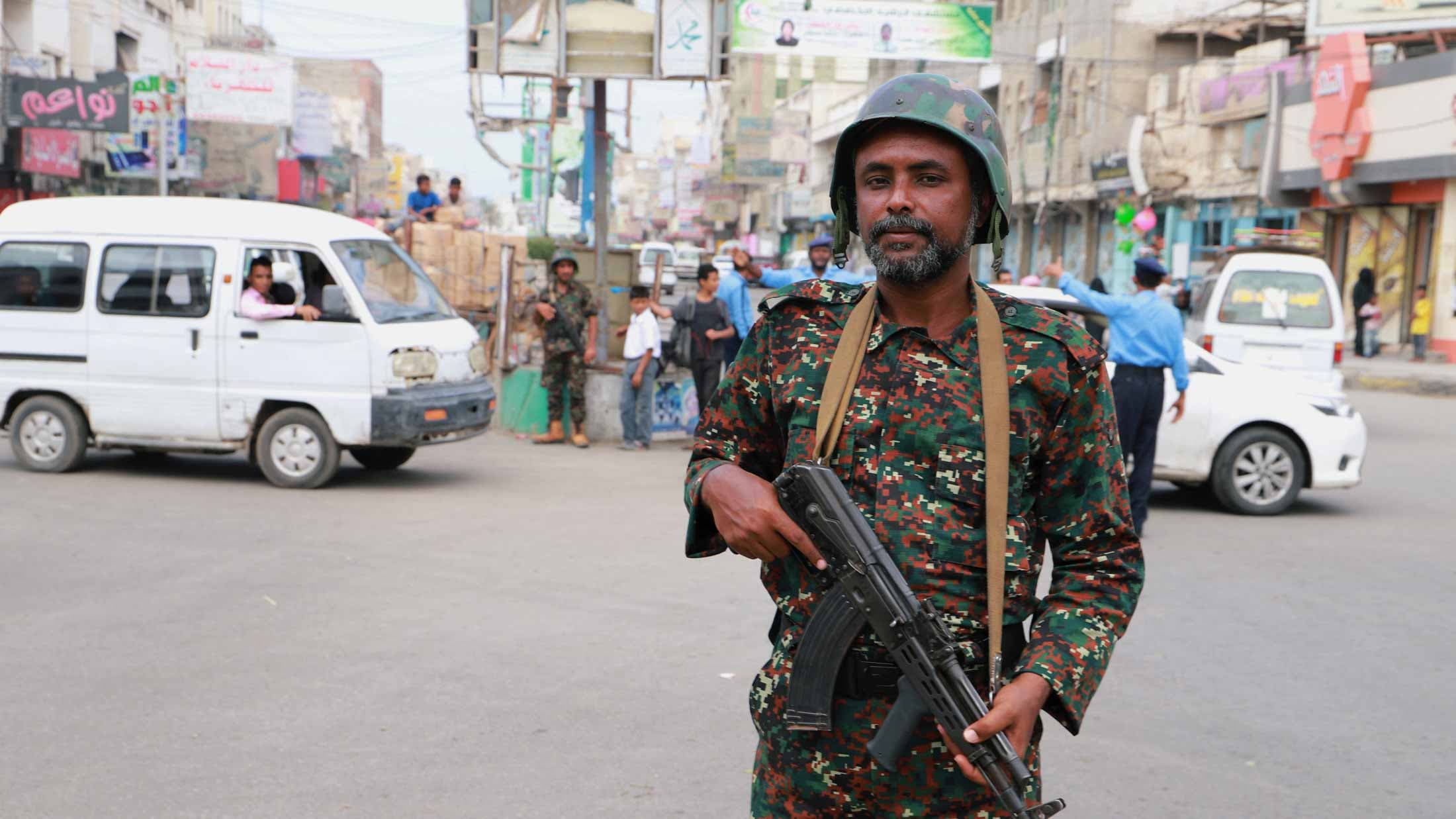 A soldier stands in a road holding a gun