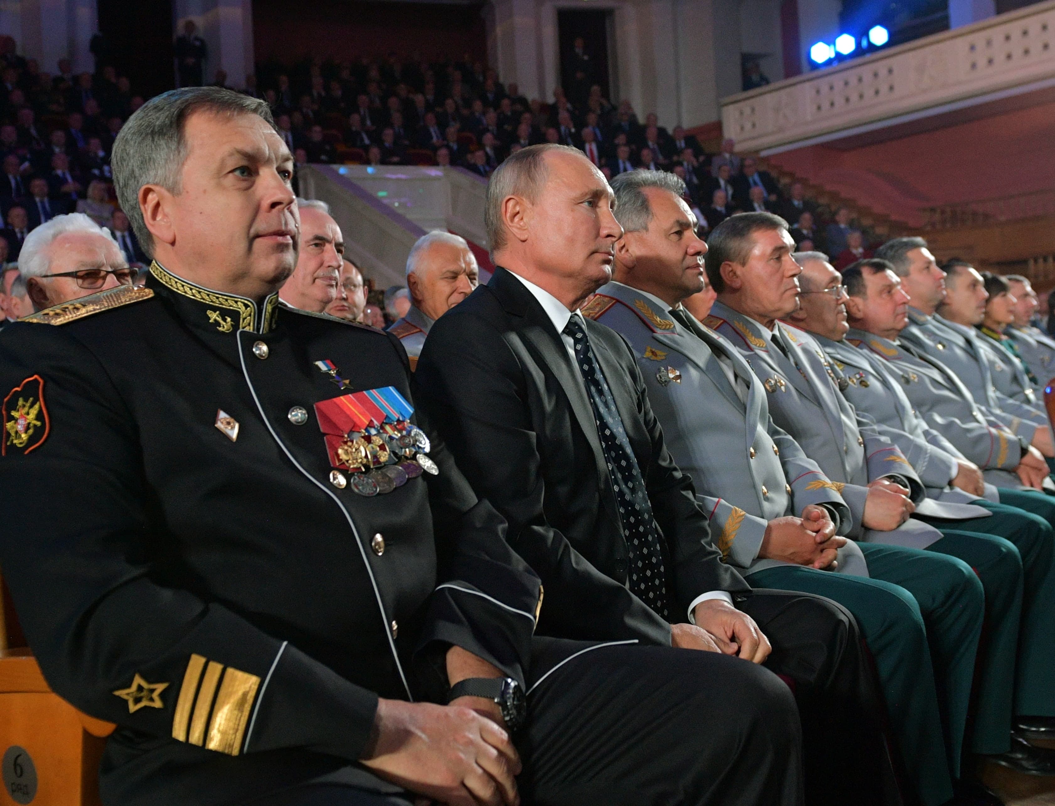 Russia's President Putin sits next to several military members