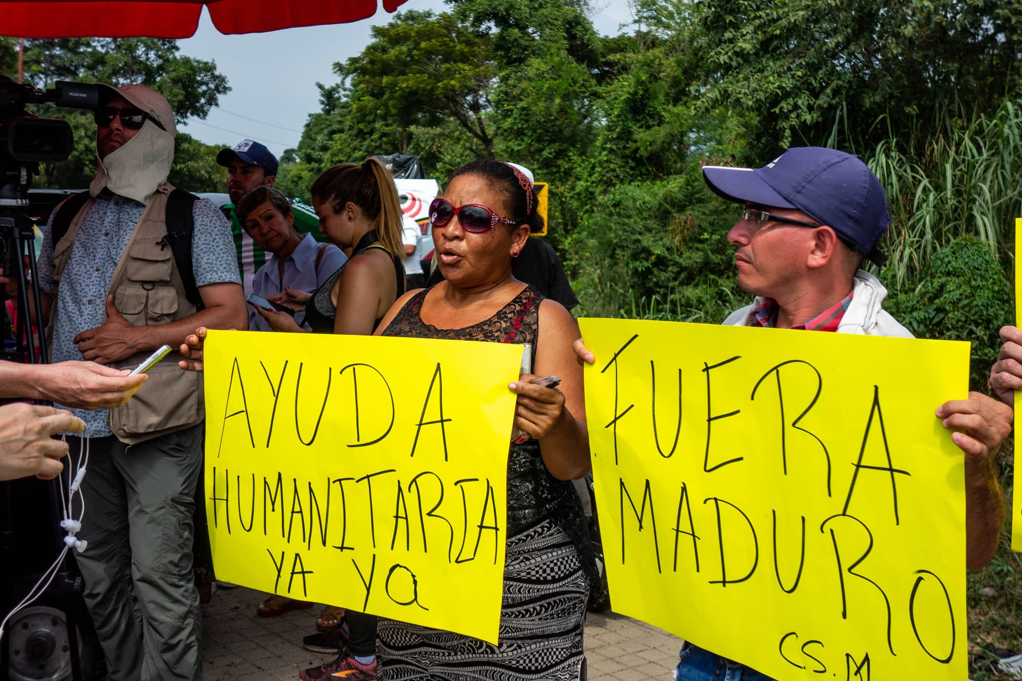 Protesters hold yellow signs with Spanish words.