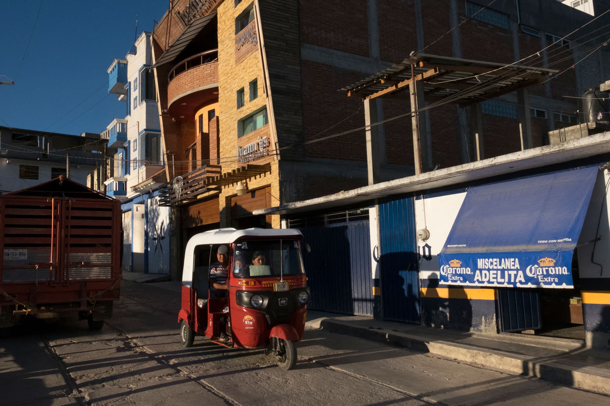 A three-wheel motorcycle taxi is shown driving by Juann’as Ristorante pizzeria in Tlaxiaco.