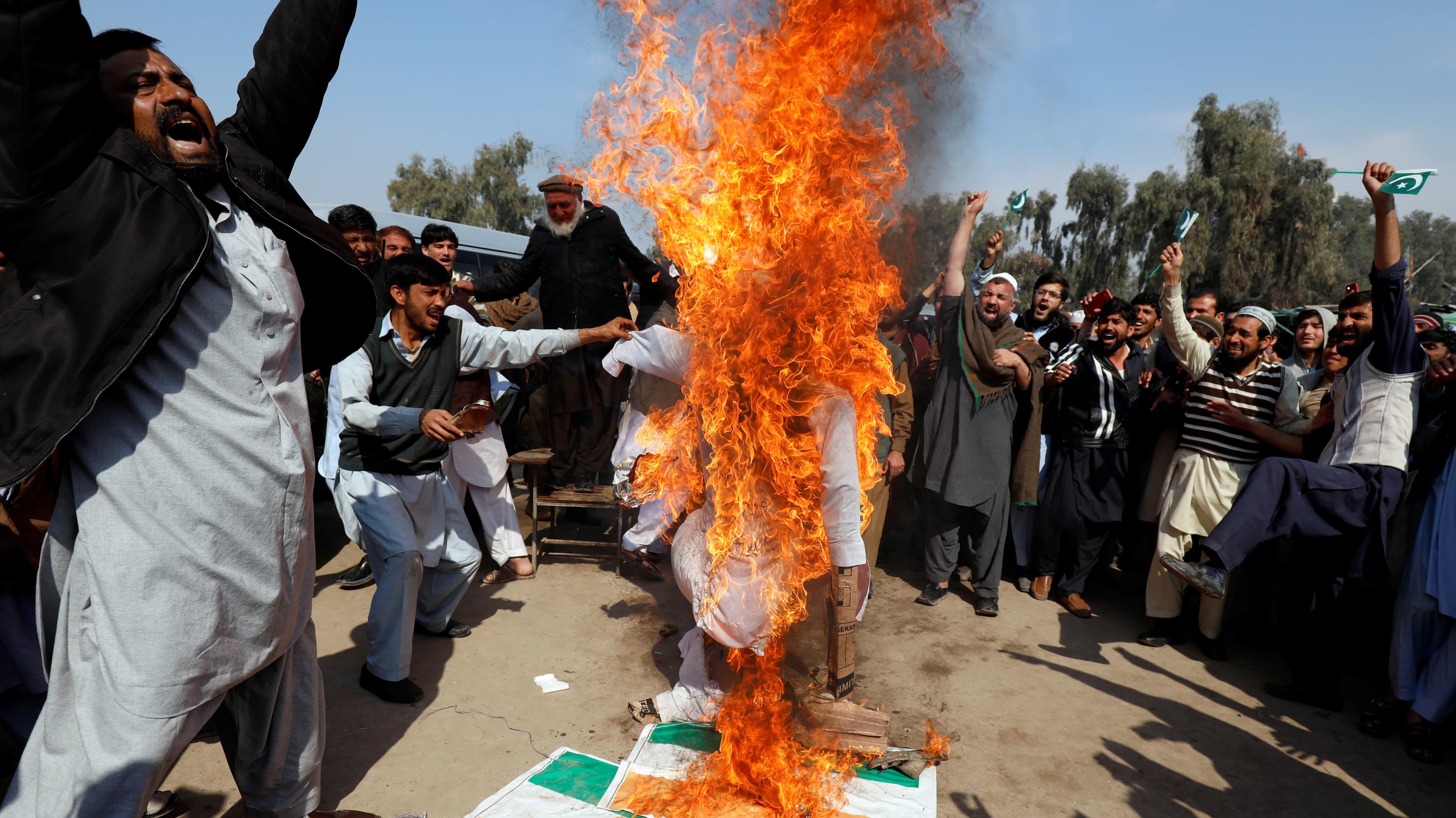 People chant slogans as they burn an effigy