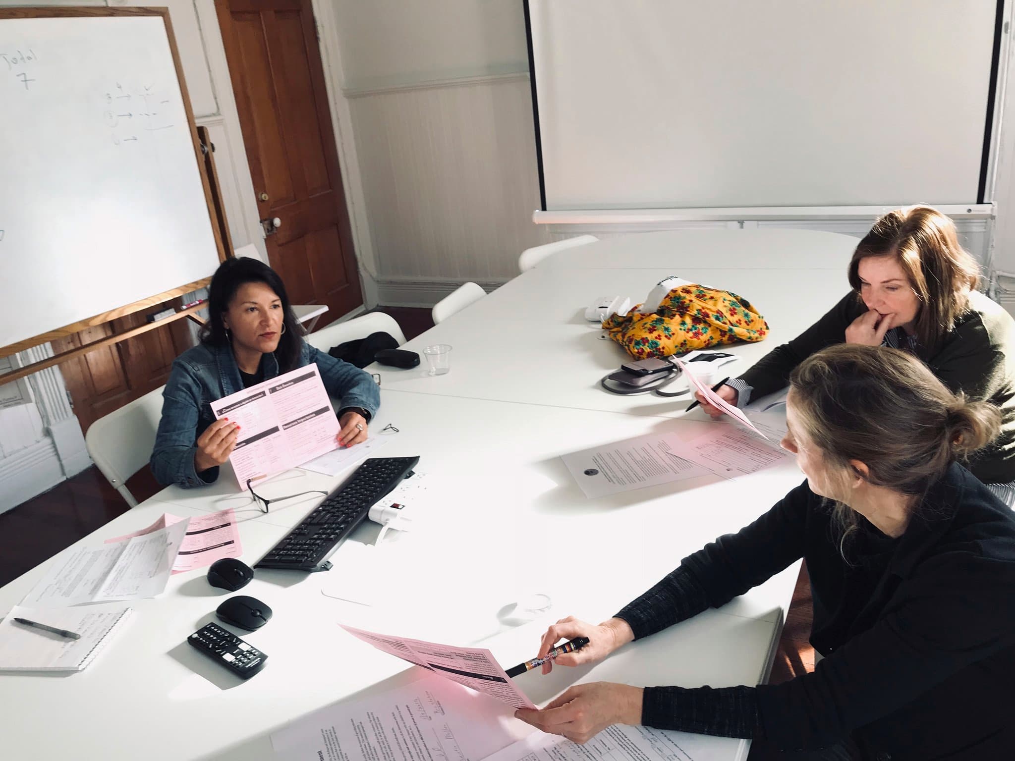 Therapists sit around a white table holding pink papers