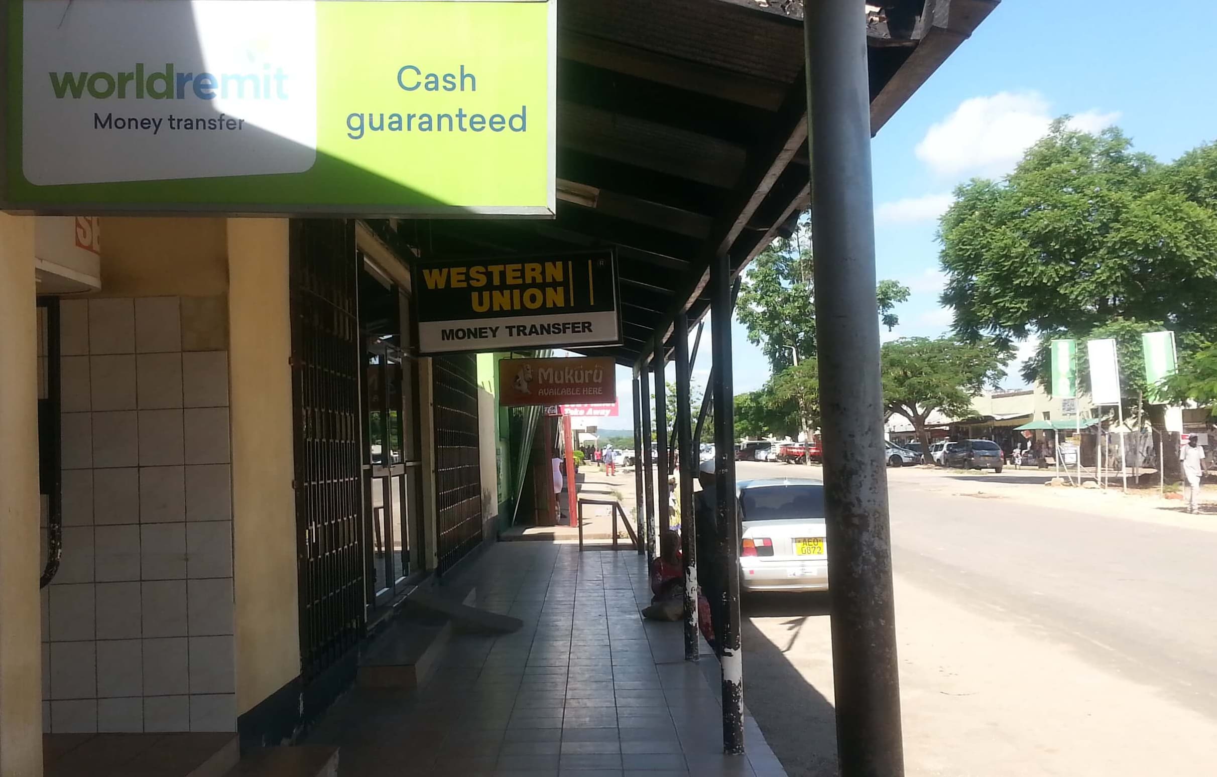 A strip of closed offices and empty sidewalk with a single woman waiting for offices to open.