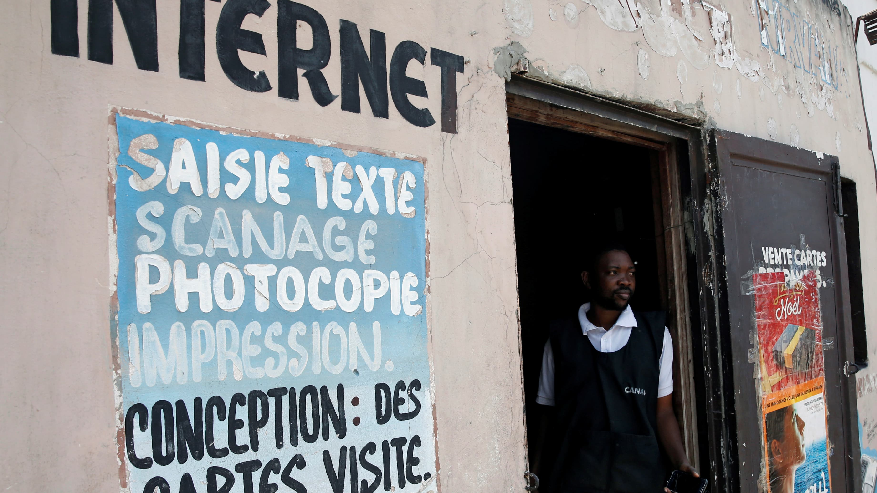 Man stands at entrance to internet cafe.