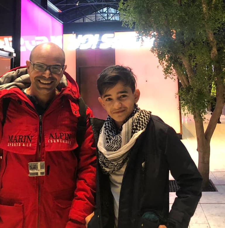 Man with red jacket stands next to son with black jacket.