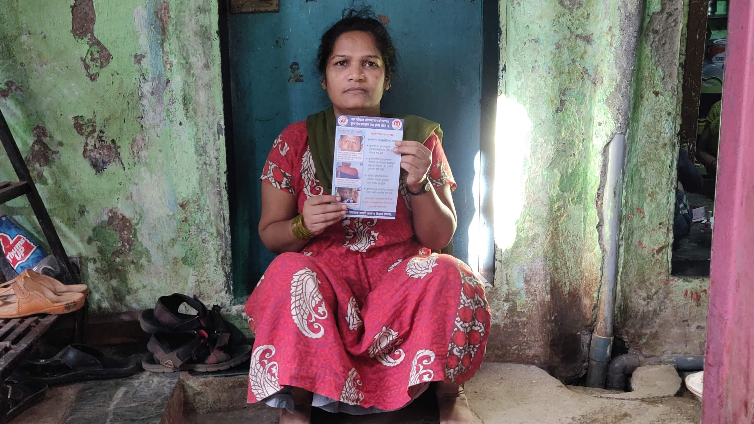 A woman holds a pamphlet in front of a blue door.