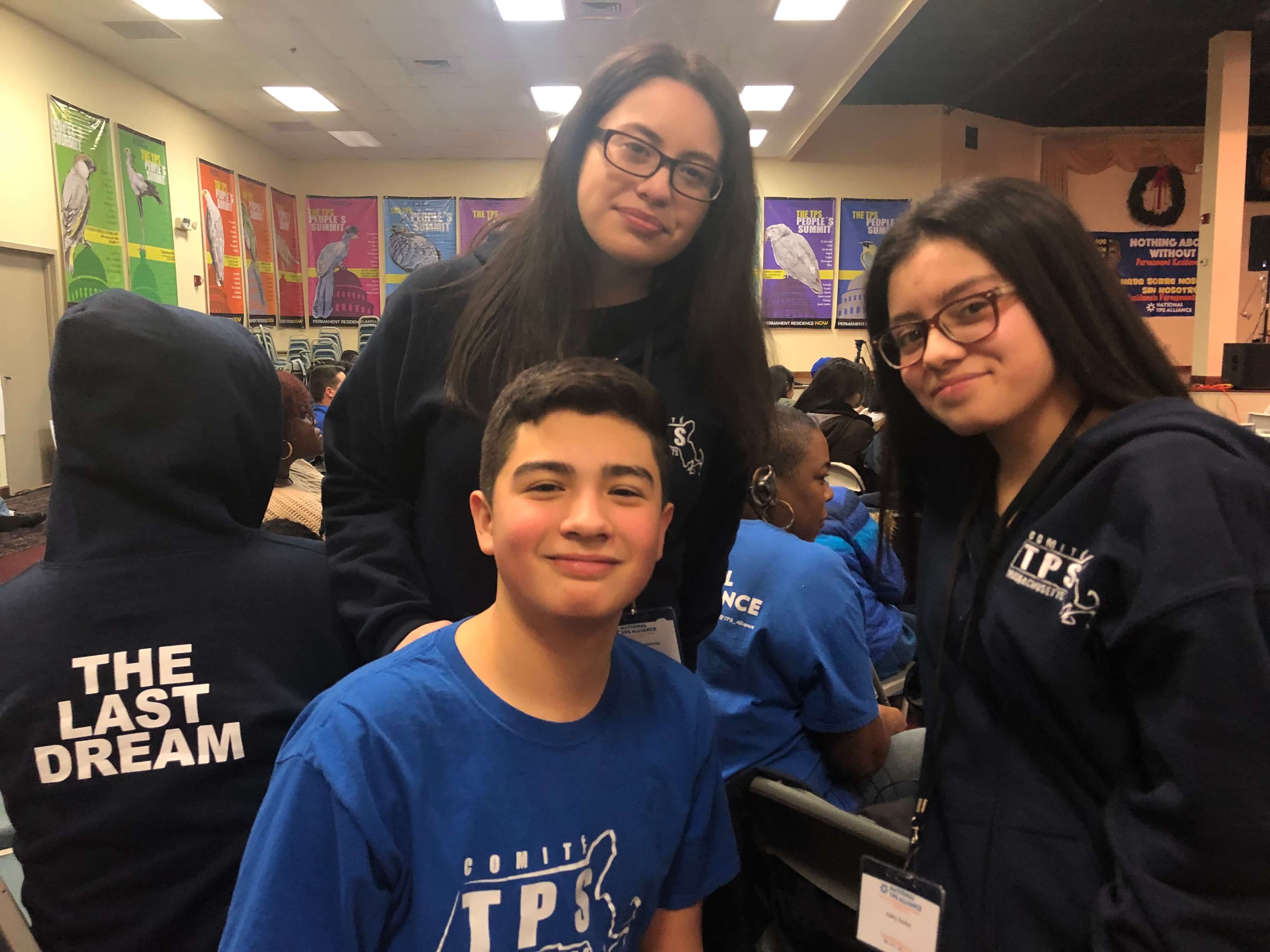 Three kids look straight at the camera as they wear dark blue