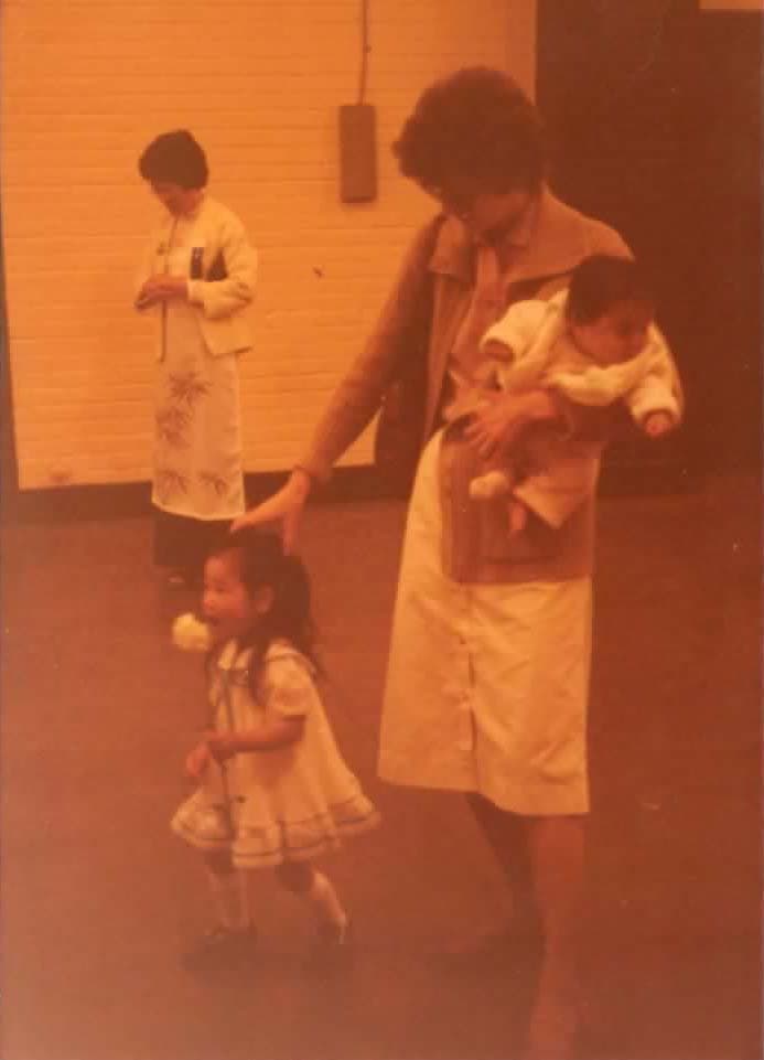 A little girl runs with a woman holding a baby