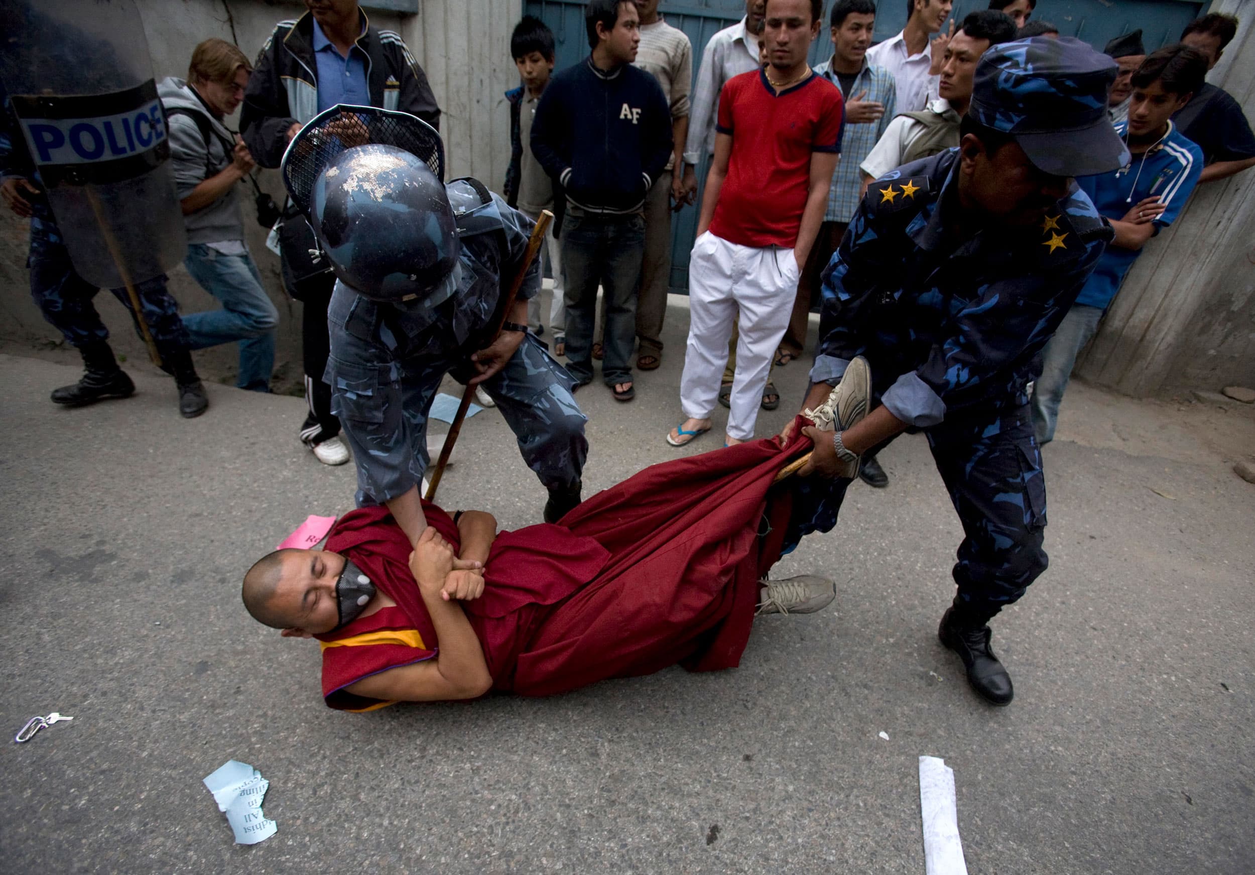 A monk is being dragged by police officers