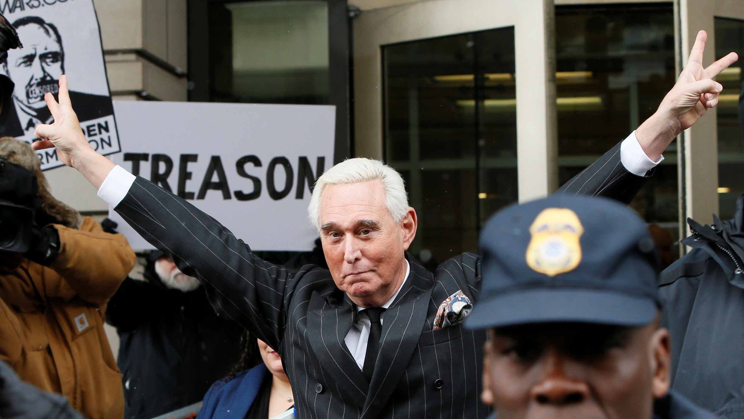 A man in a suit holds his fingers in Vs like Richard Nixon