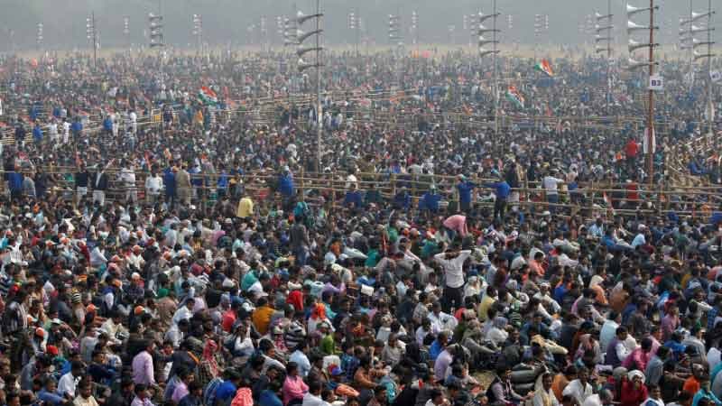 Thousands of people are packed into an outdoor space listening to speakers