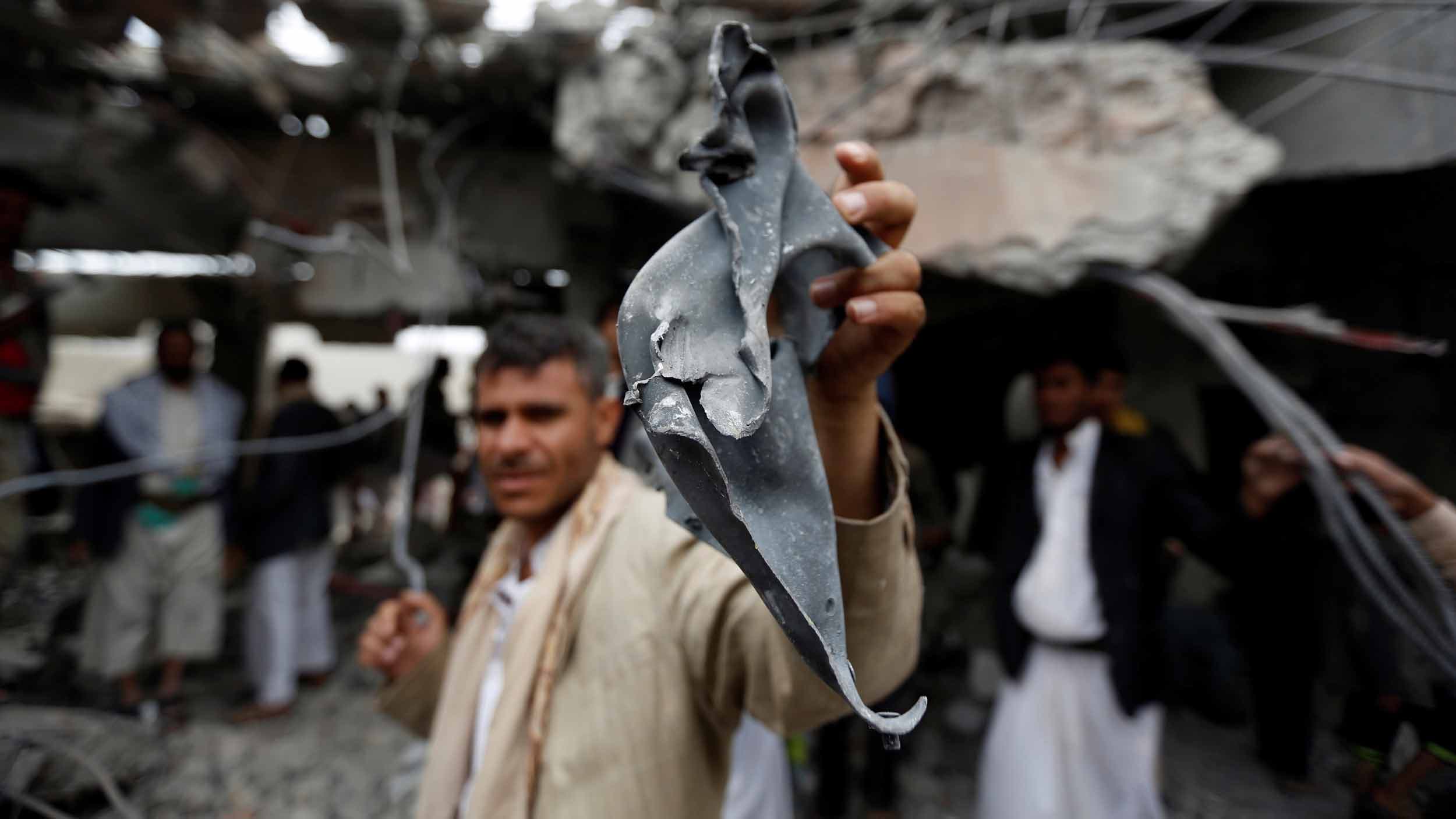 A man holds a blackened piece of metal toward the camera