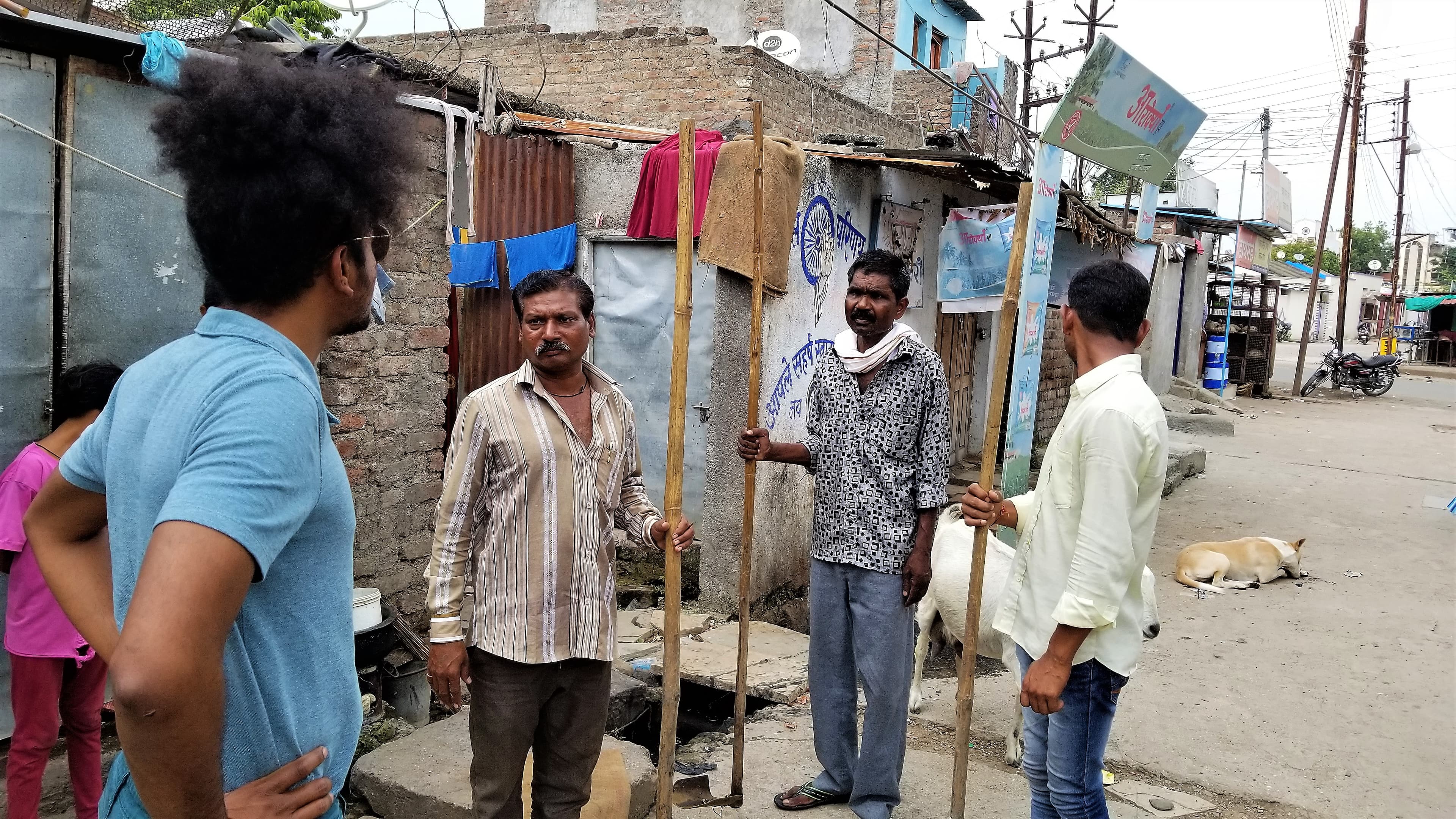 A young man stands and talks with other men holding poles
