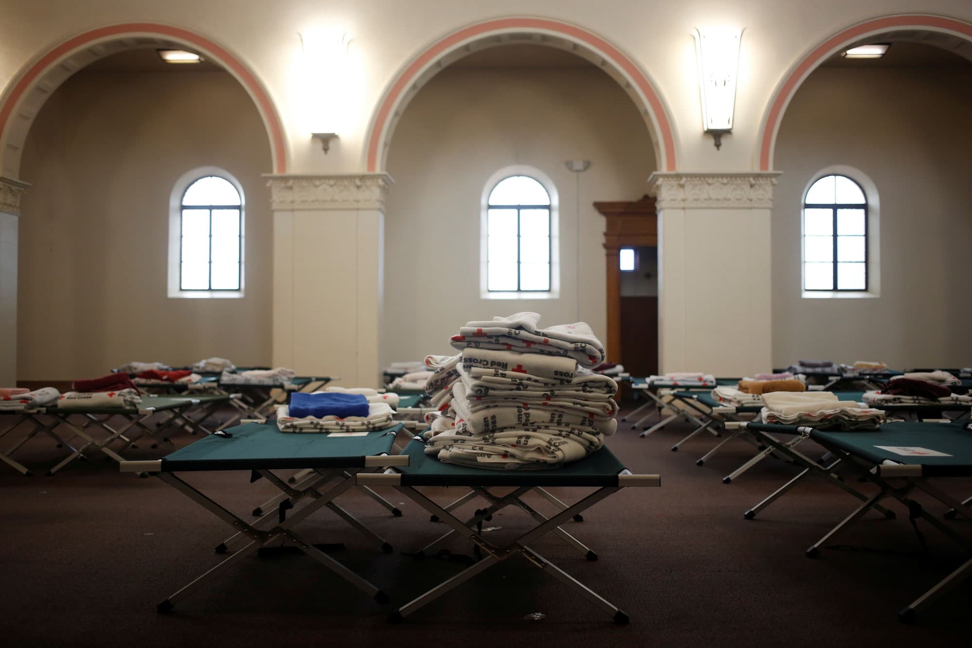 Stacks of blankets are show sitting on cots in the chapel of the monastery.