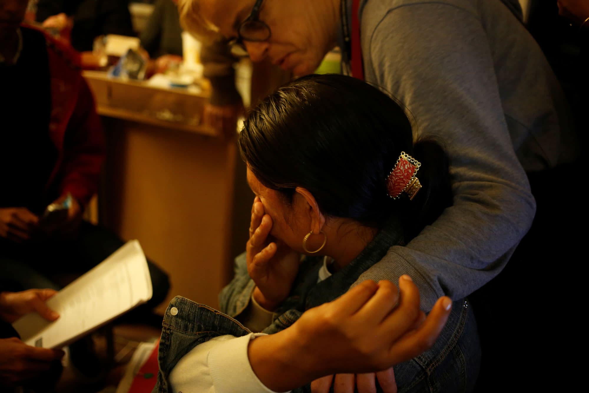 A volunteer is shown comforting a Guatemalan woman show has her hand to her face.