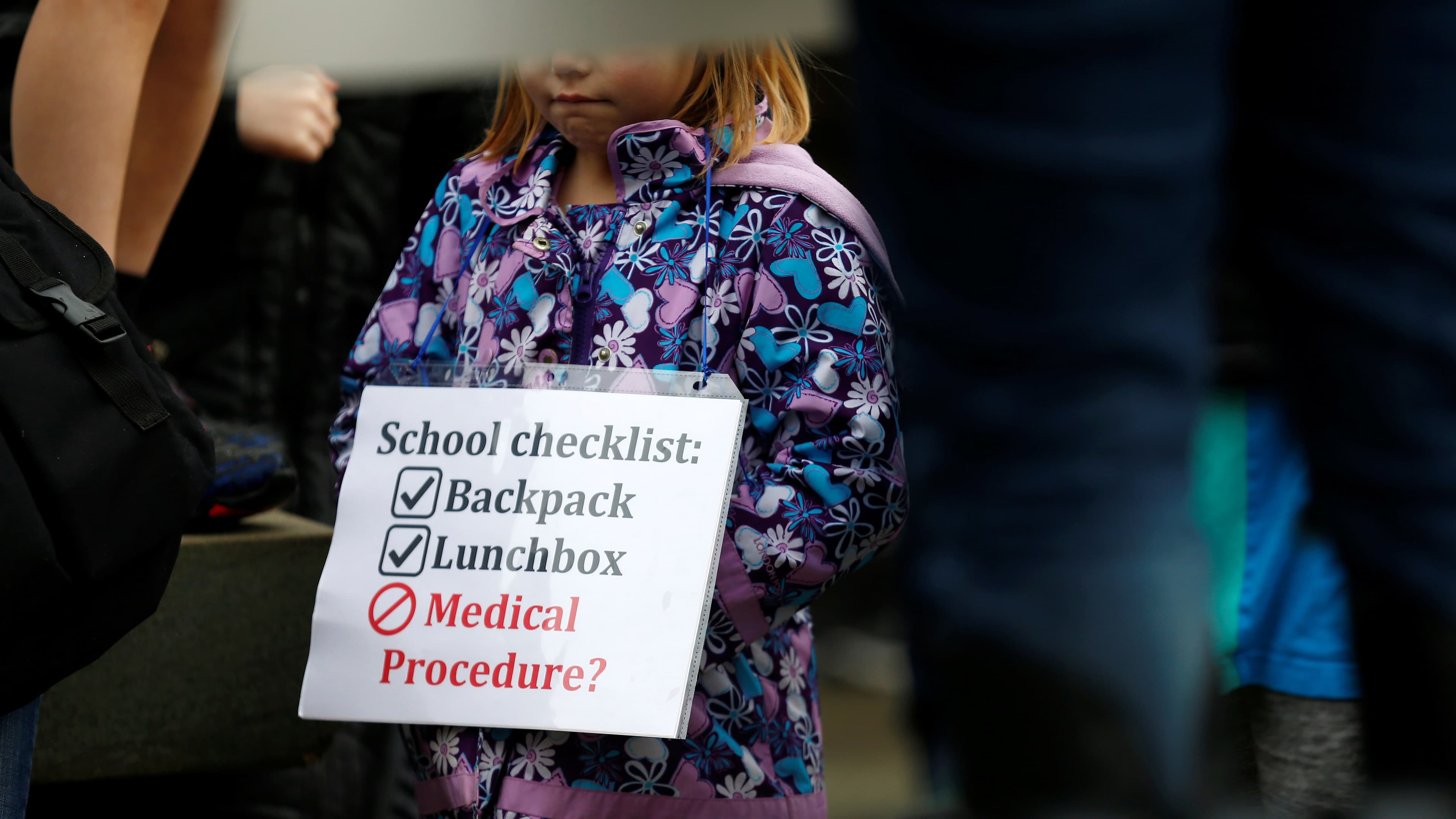 a child's face is covered while holding a sign