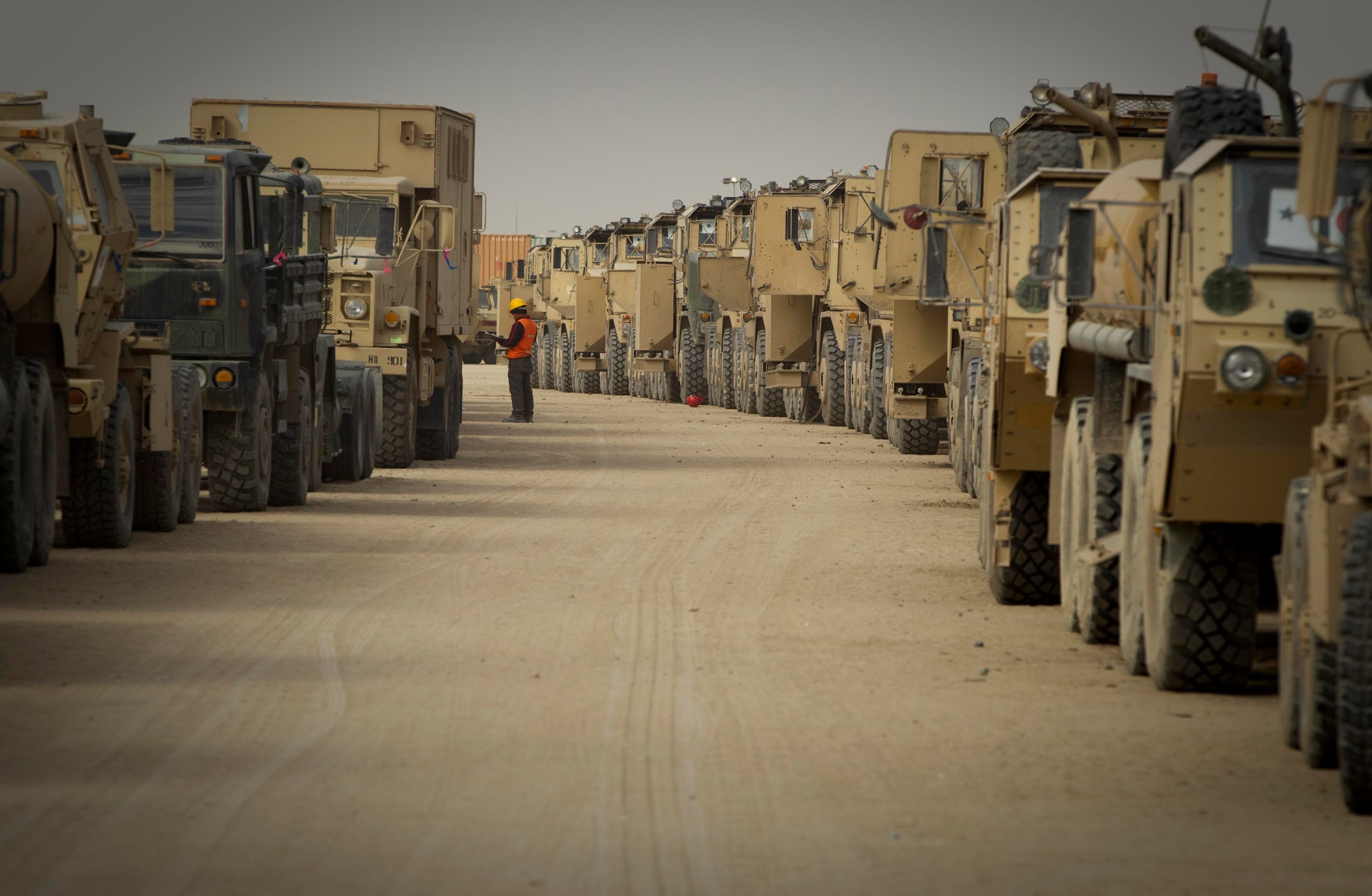 A contractor walks between trucks