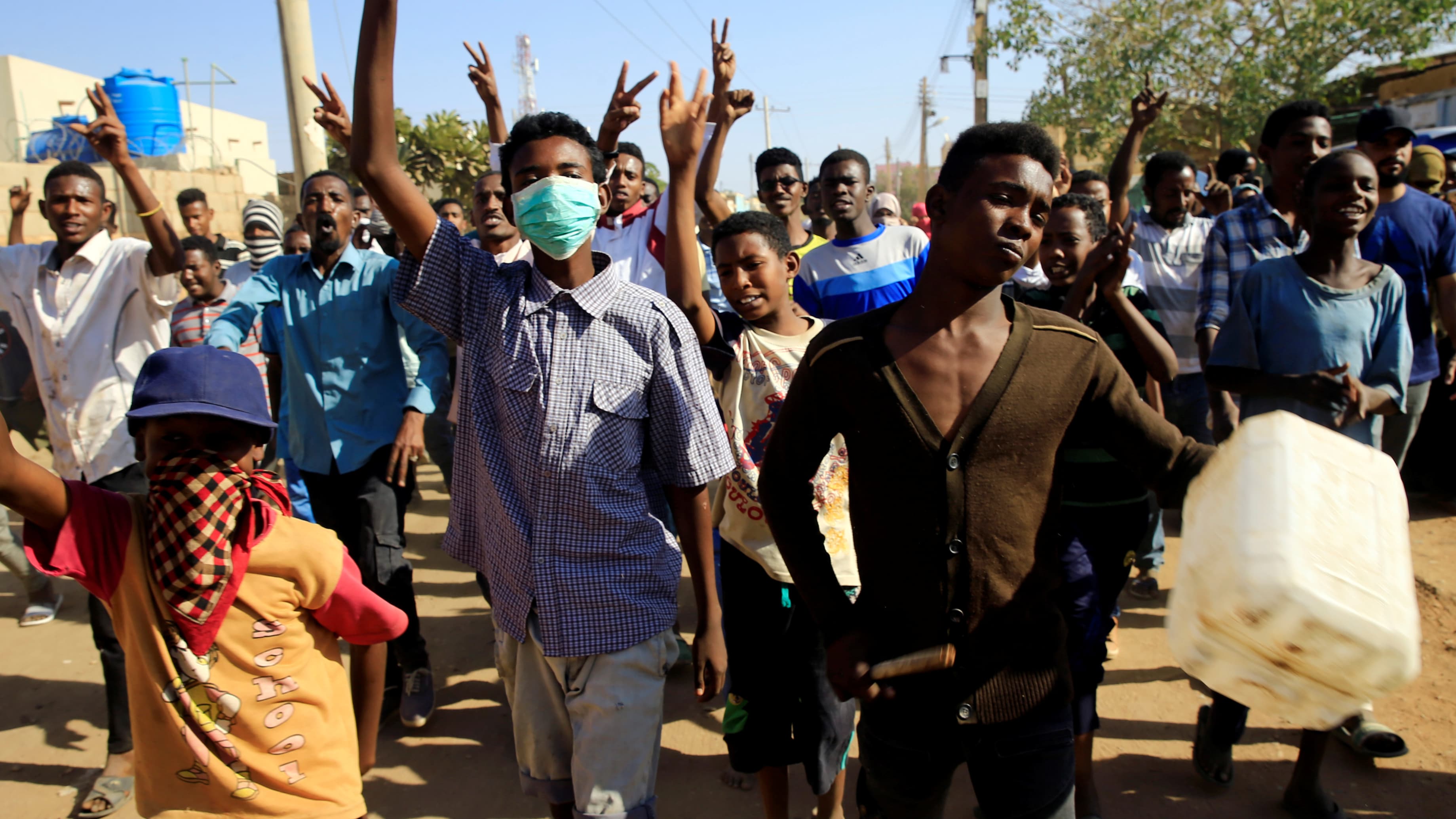 Youth protest wearing wearing bandanas on their faces and carrying a can in Khartoum.