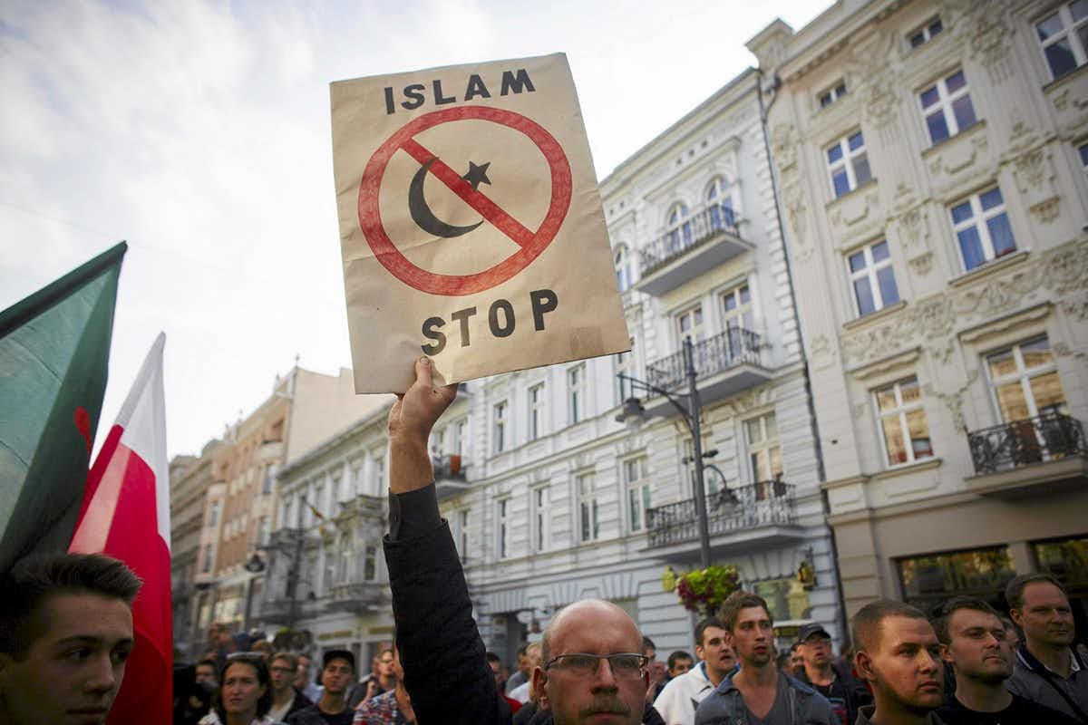 a white man holds up a sign that reads 