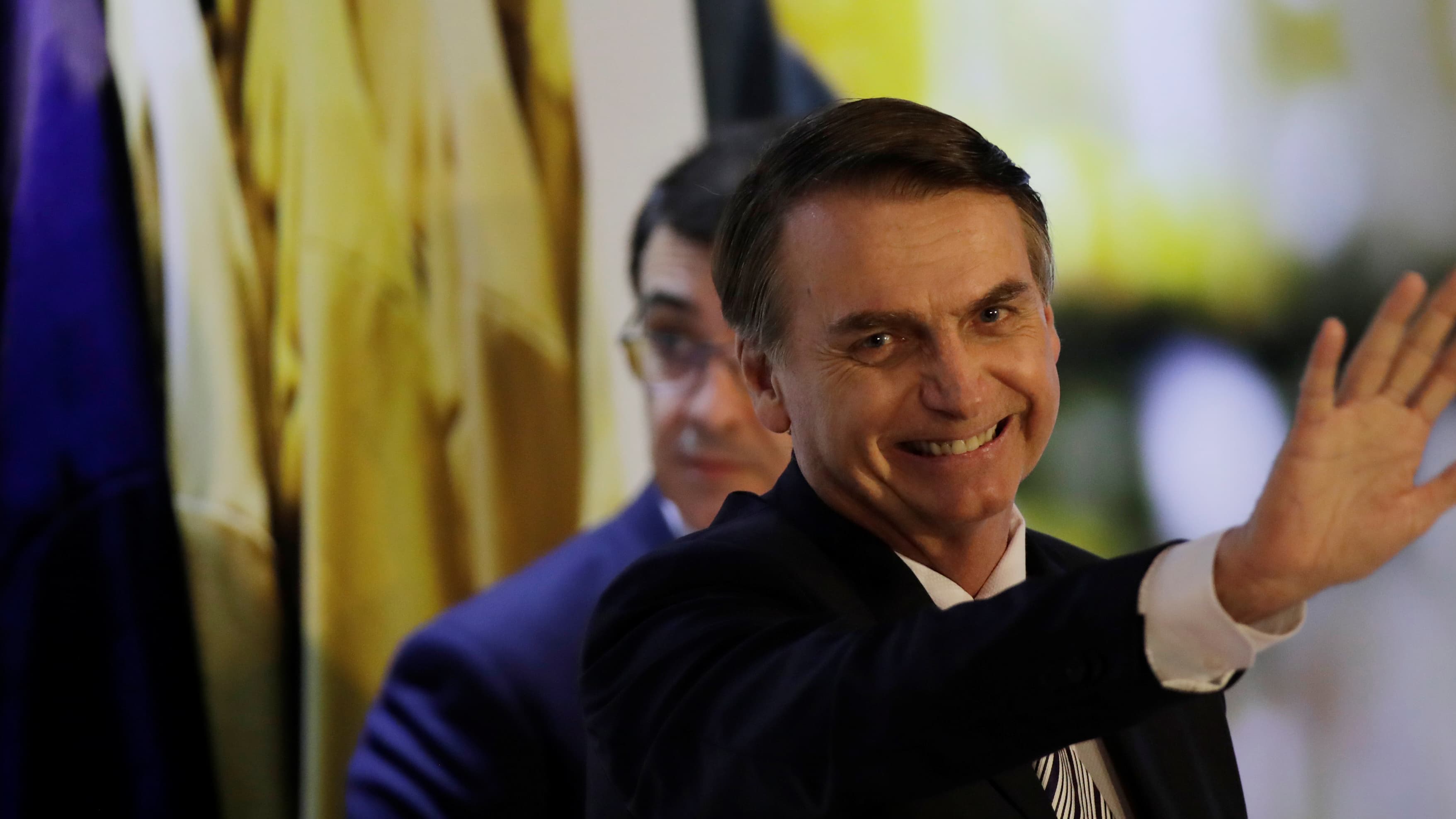 Bolsonaro smiles and puts his hand out