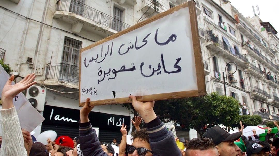 A protester holds up a sign in Arabic writing.