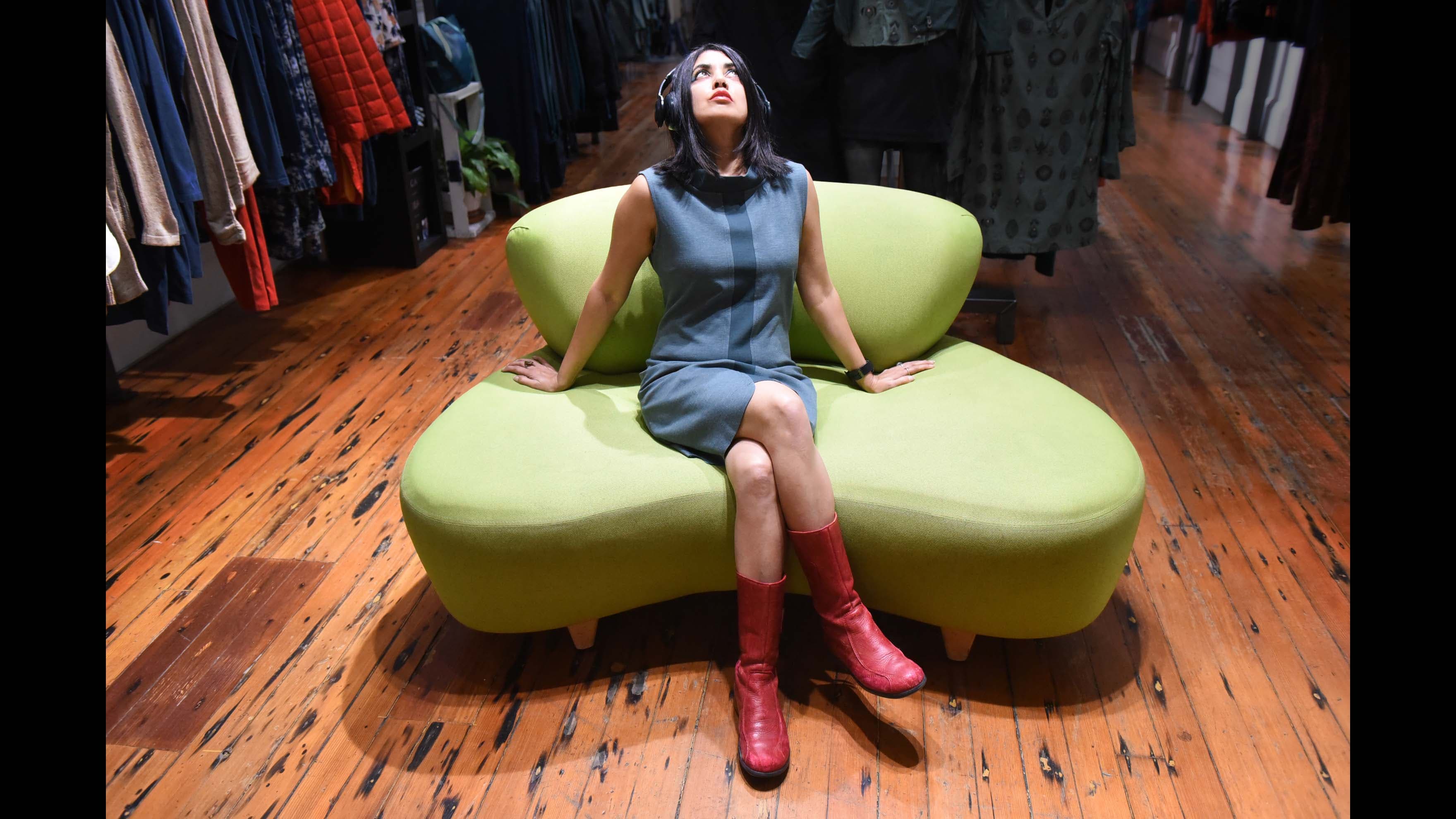 A woman wearing headphones leans back on a settee staring at the ceiling in an artistic portrait