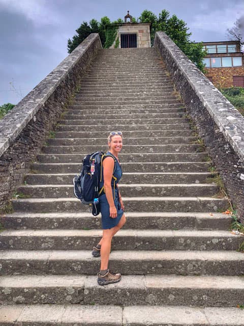 A woman poses at the bottom of a stone staircase