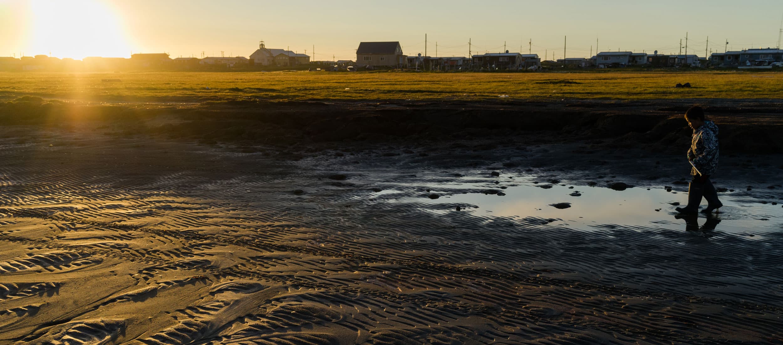 A person walks through a puddle in Shismaref, Alaska.