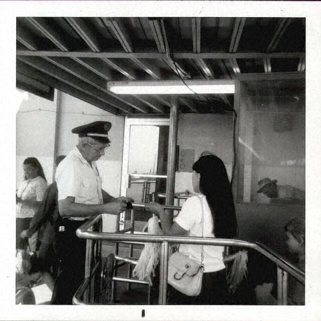 A man in uniform inspects papers from a woman