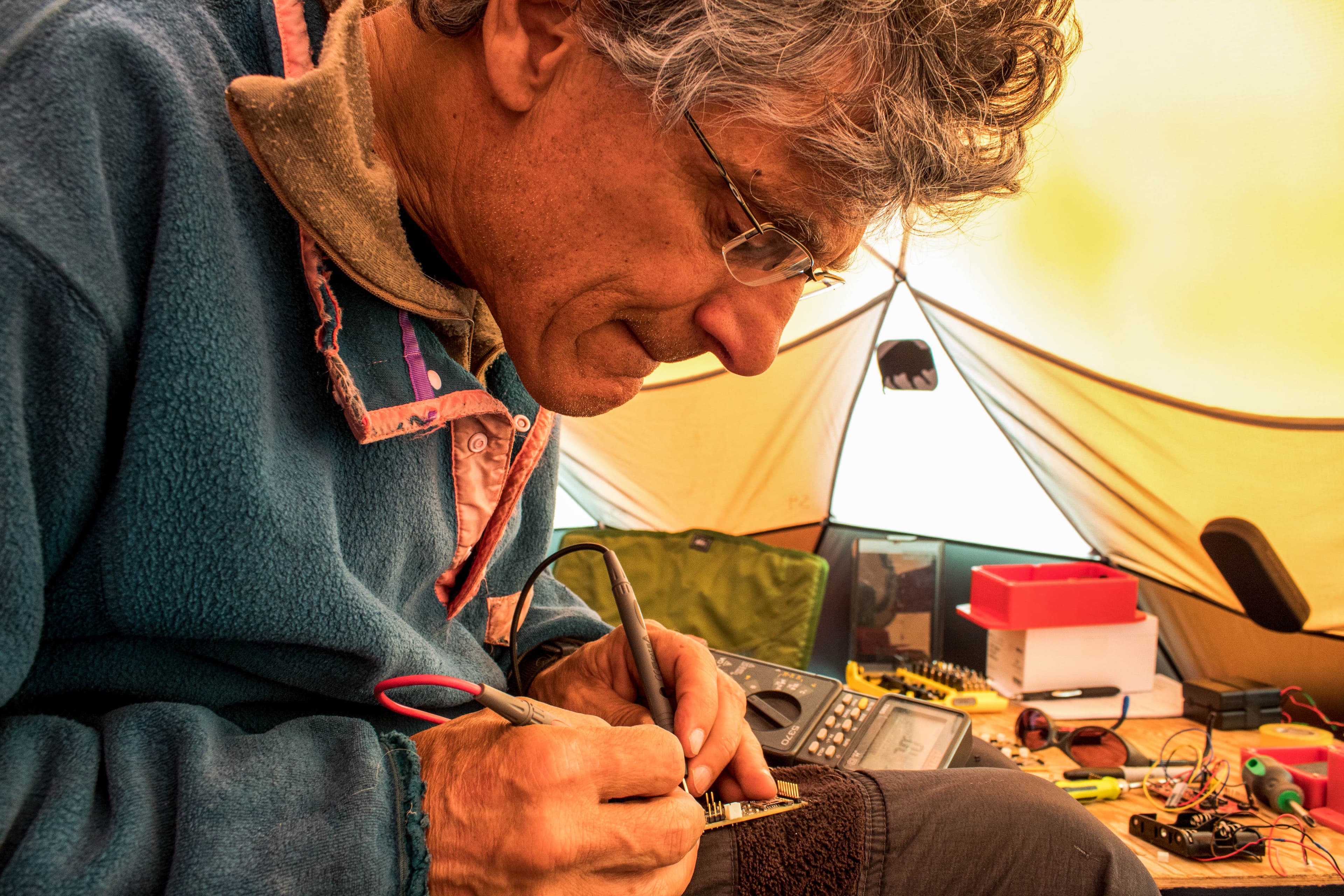 University of Wyoming glaciologist Neil Humphrey works on one of the tiny sensors the team sent down through a bore hole to collect information about the ice sheet bed.