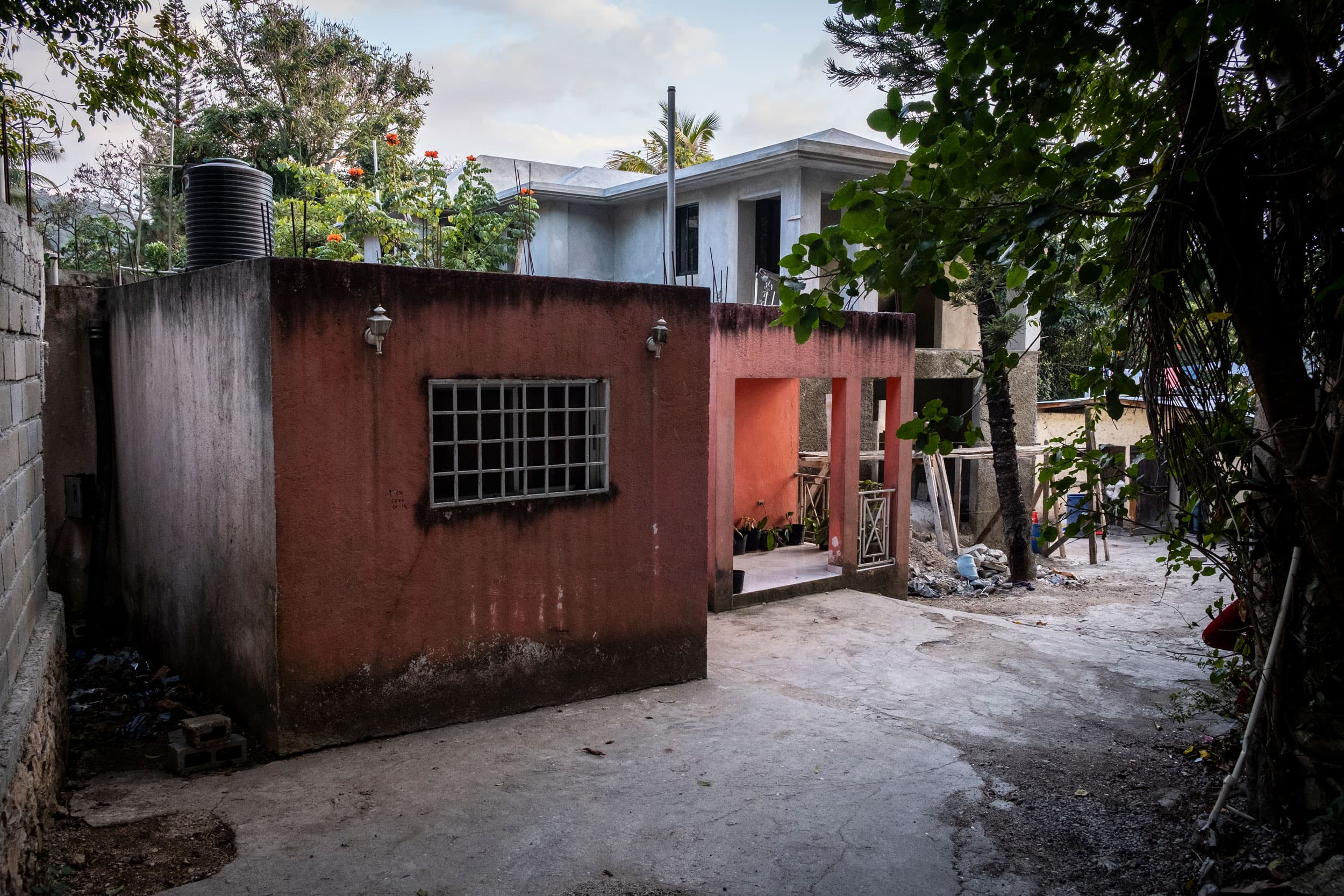 A single story, red building is shown with a metal grate covering a window.