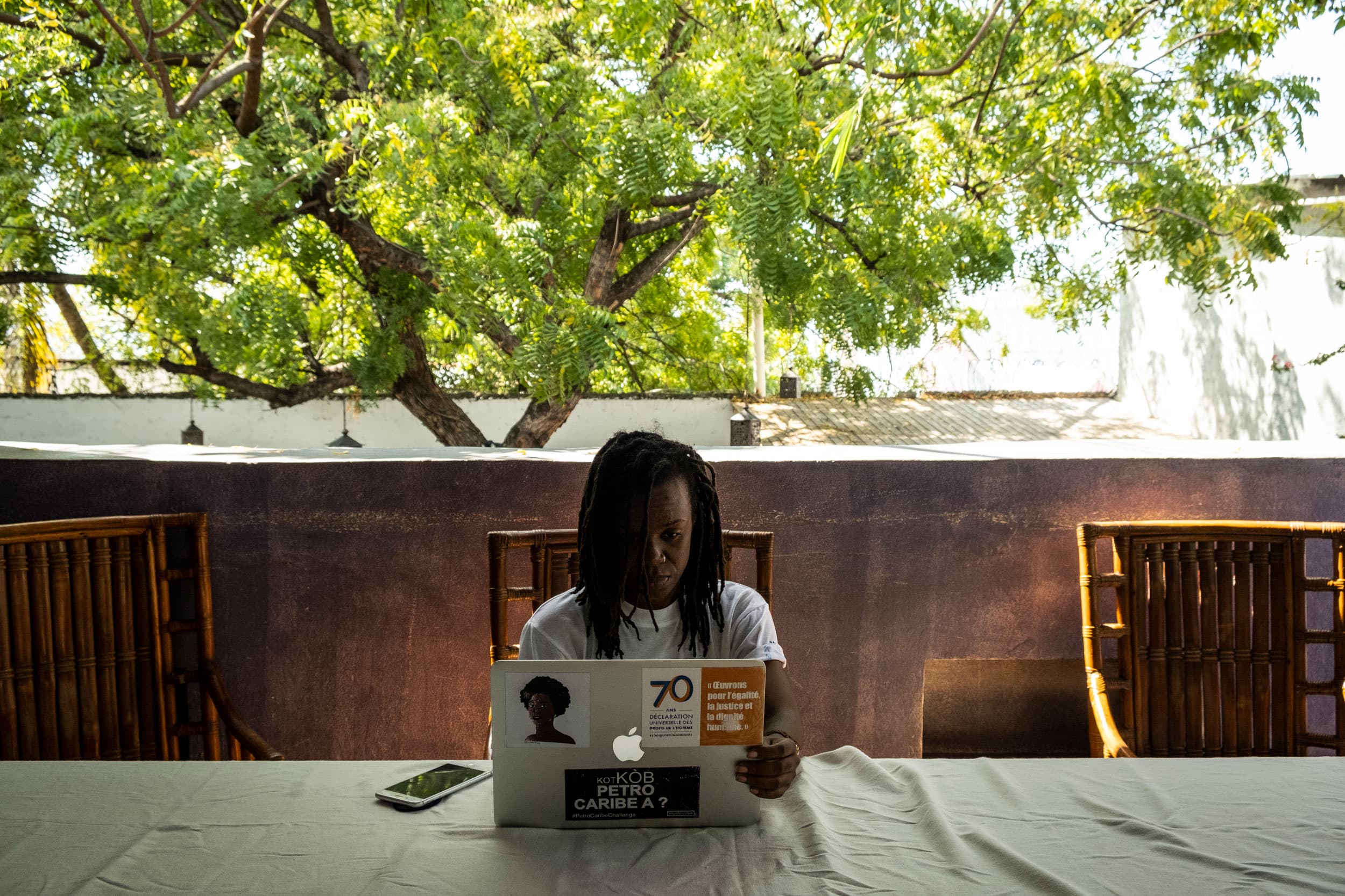 A woman is shown sitting a a table in a restaurant with her laptop open.