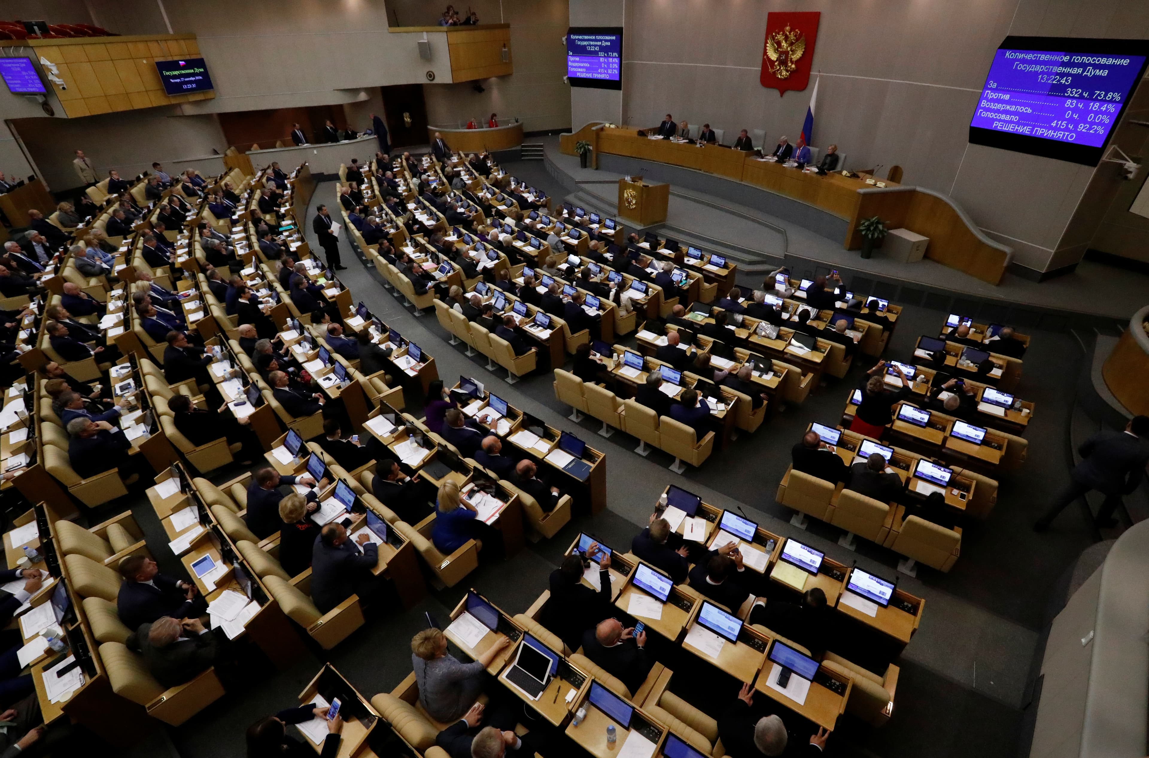 A large group of people are seated in chairs in a large room.