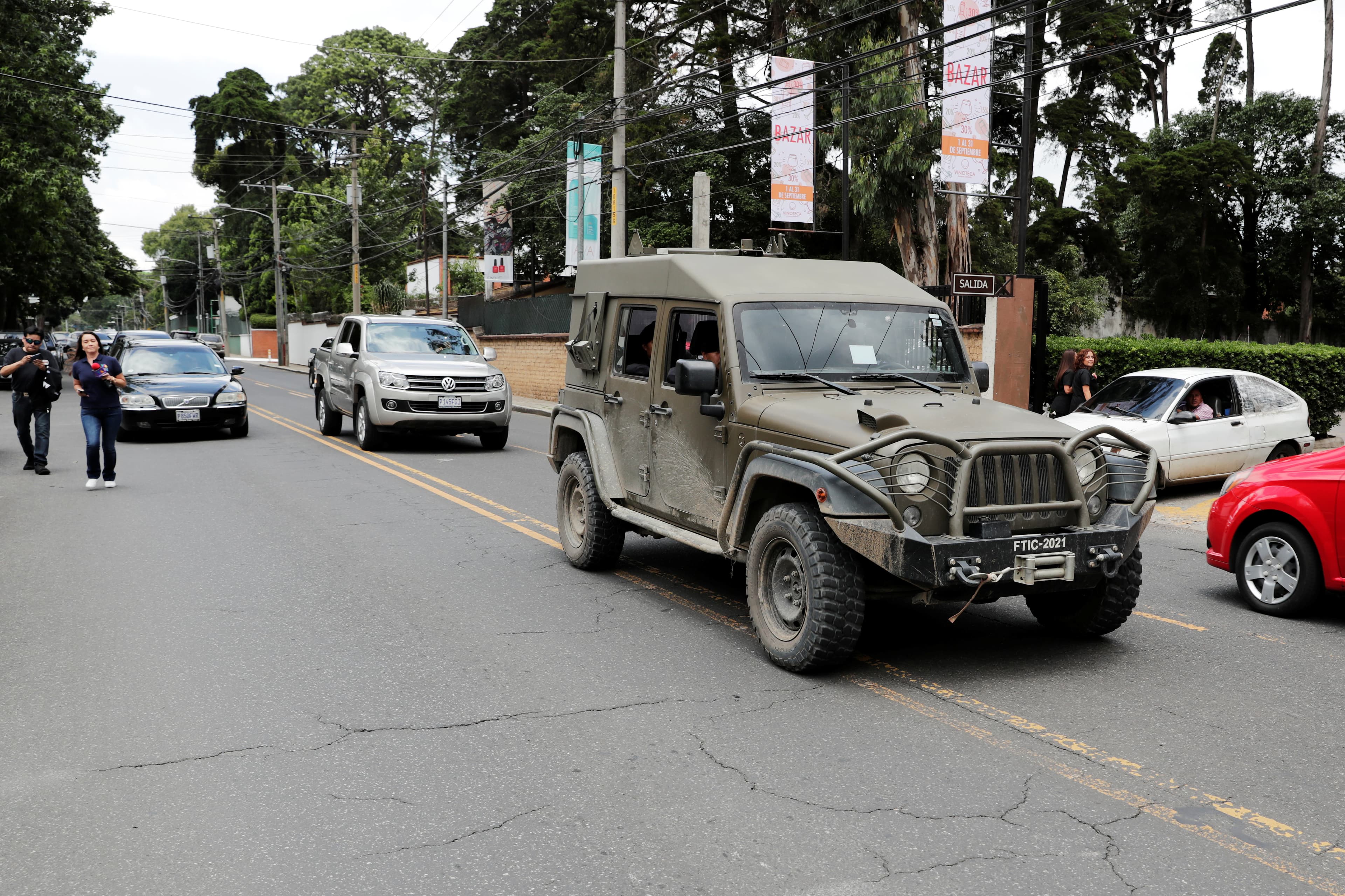 A green military truck drives on a road.