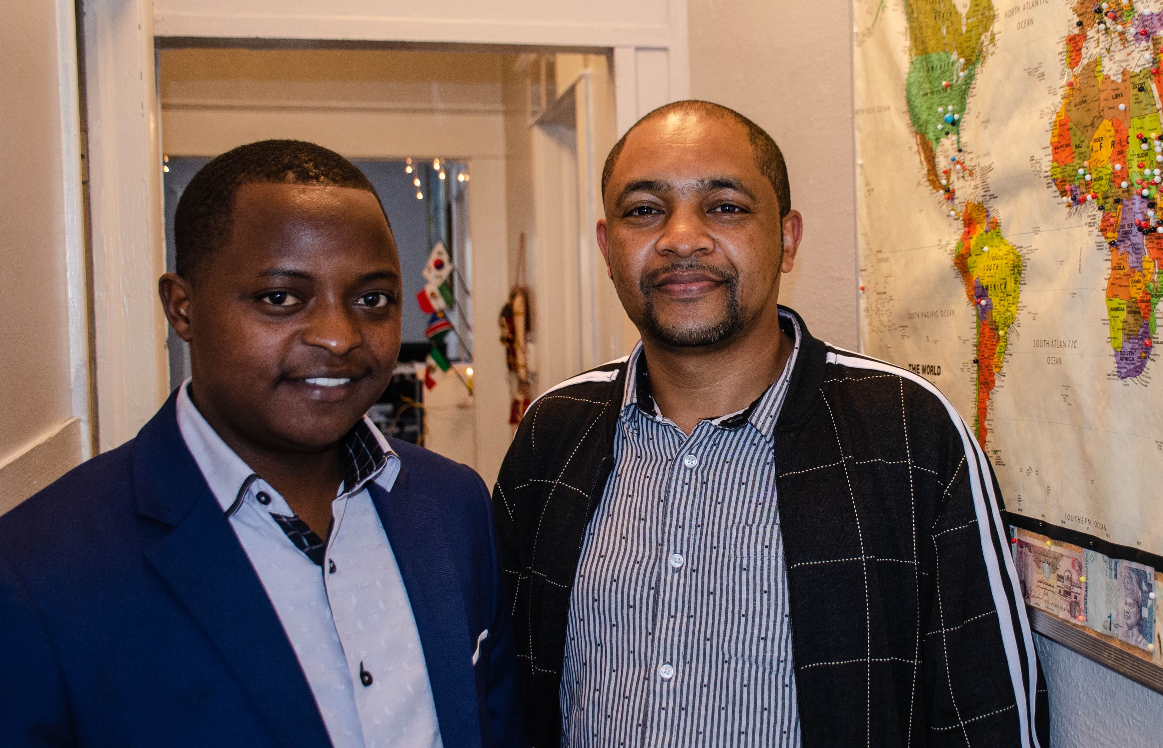 Felix Hategekimana, left, and Mekuanet Gelagay from Ethiopia stand next to a map at the Friends of Refugees center with push pins designating places from where people have relocated to Clarkston.