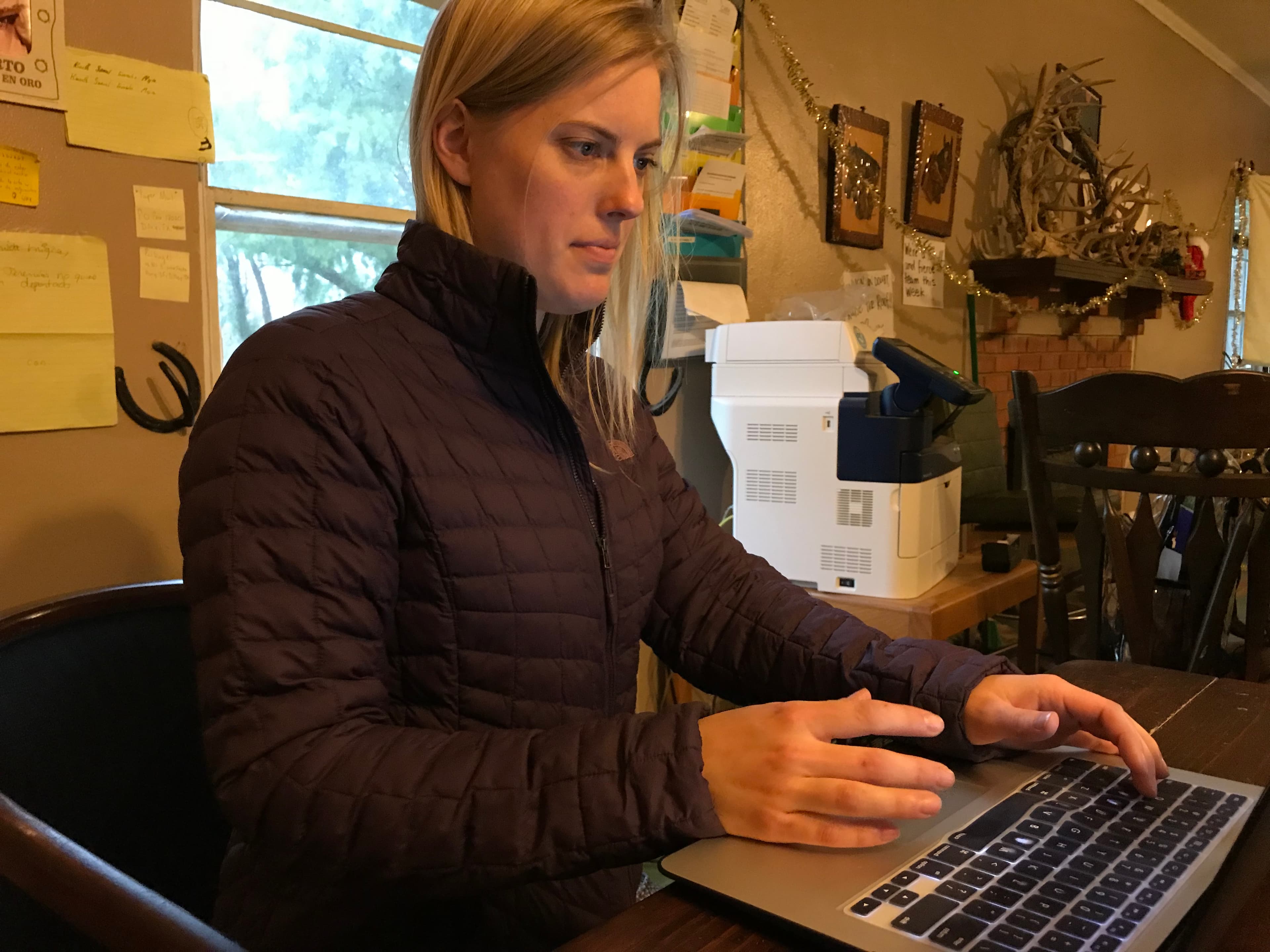 A blonde woman sits at a computer