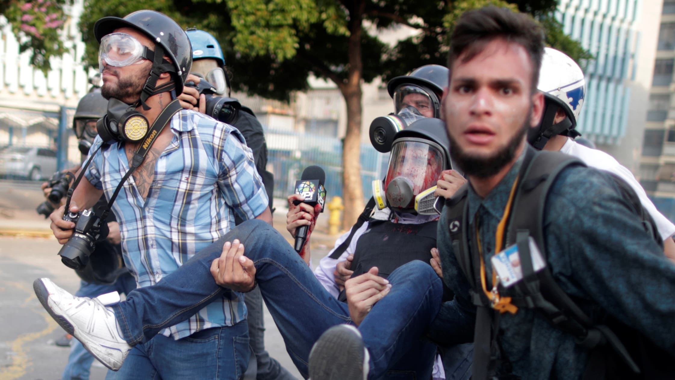 Several men wearing hard hats work together to carry an injured man