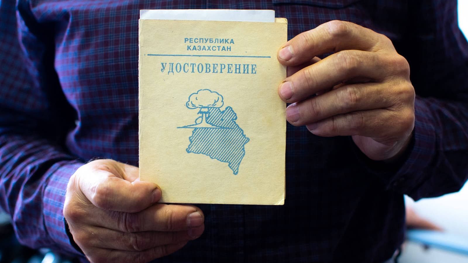 Two hands hold a beige booklet.