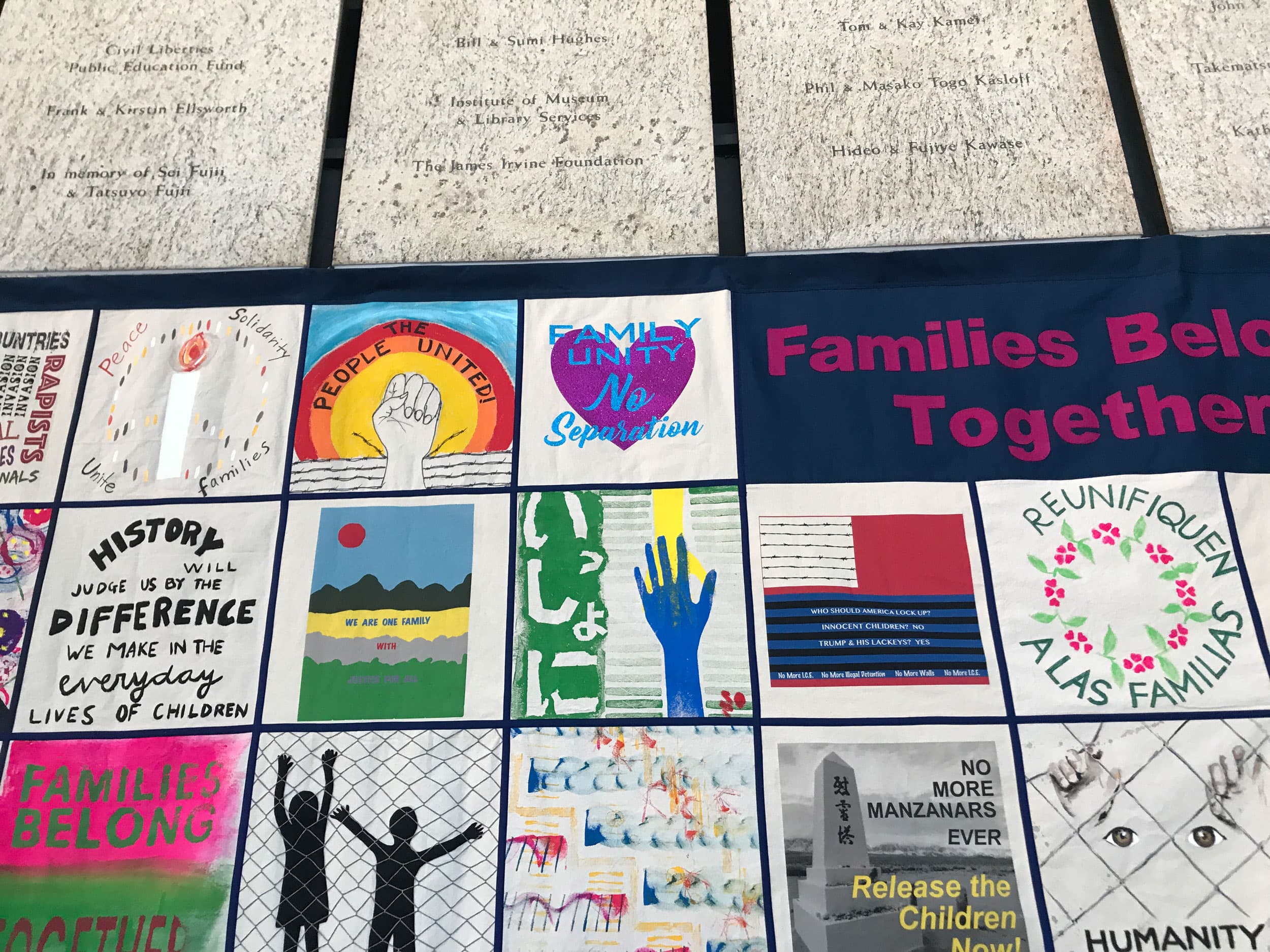 A quilt shown with many colorful squares with one that says, 