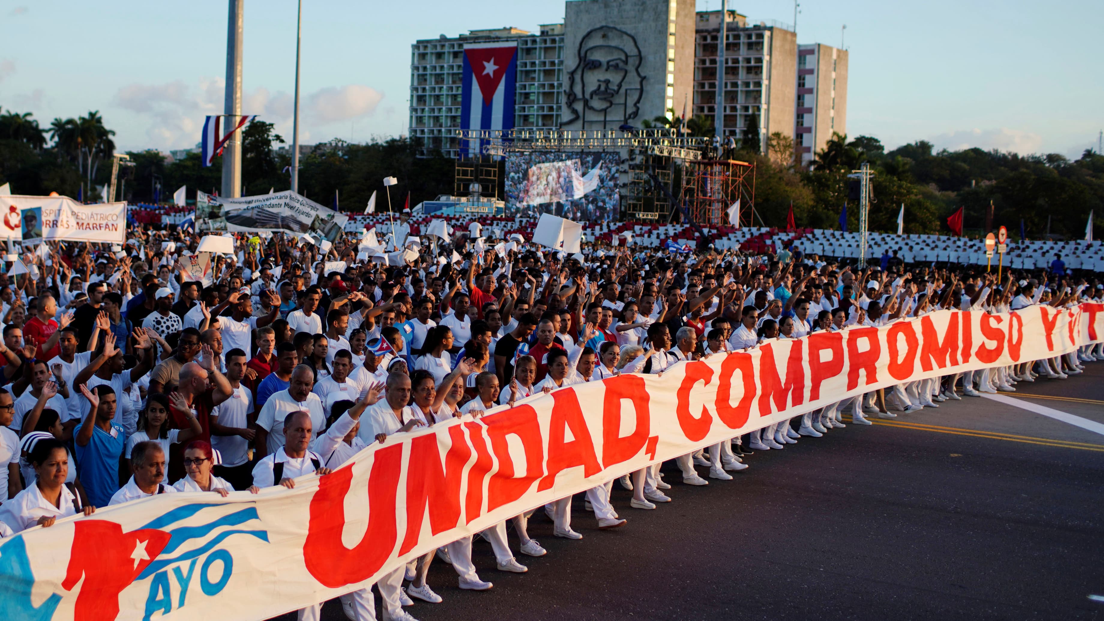 Cubans hold a sign of unity in red lettering on May Day.