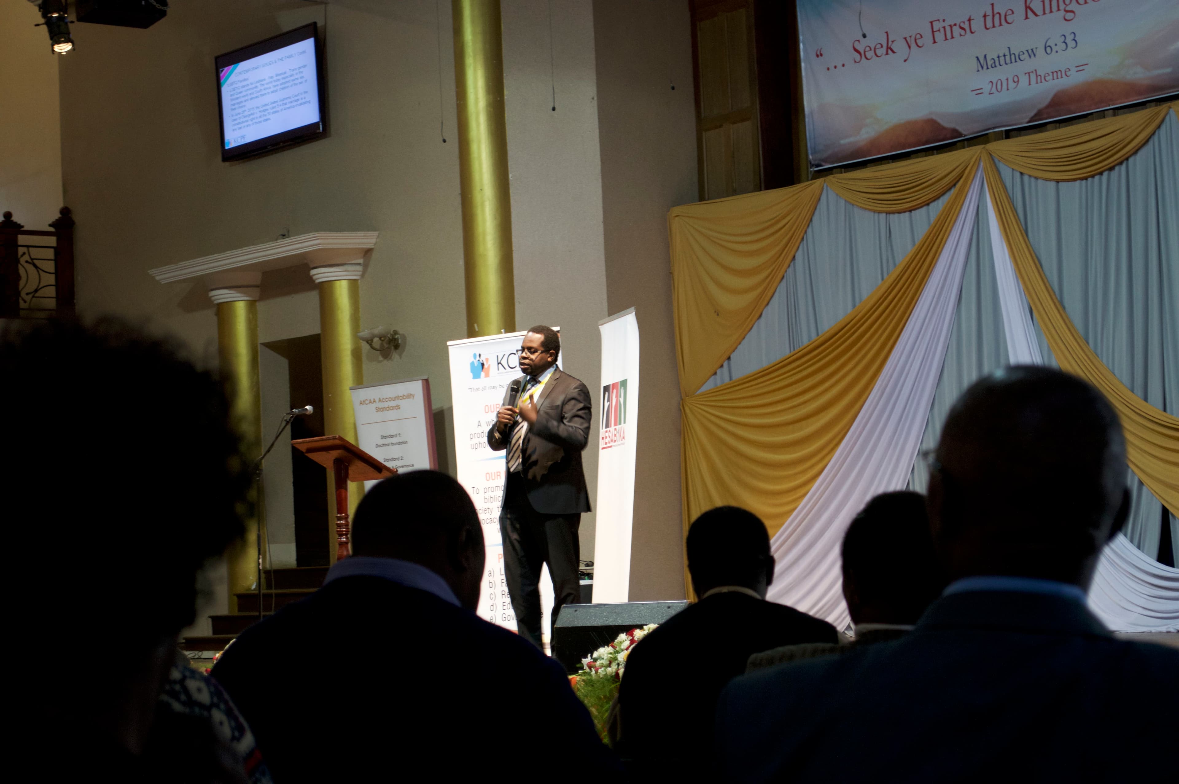A man in a suit speaks on stage.