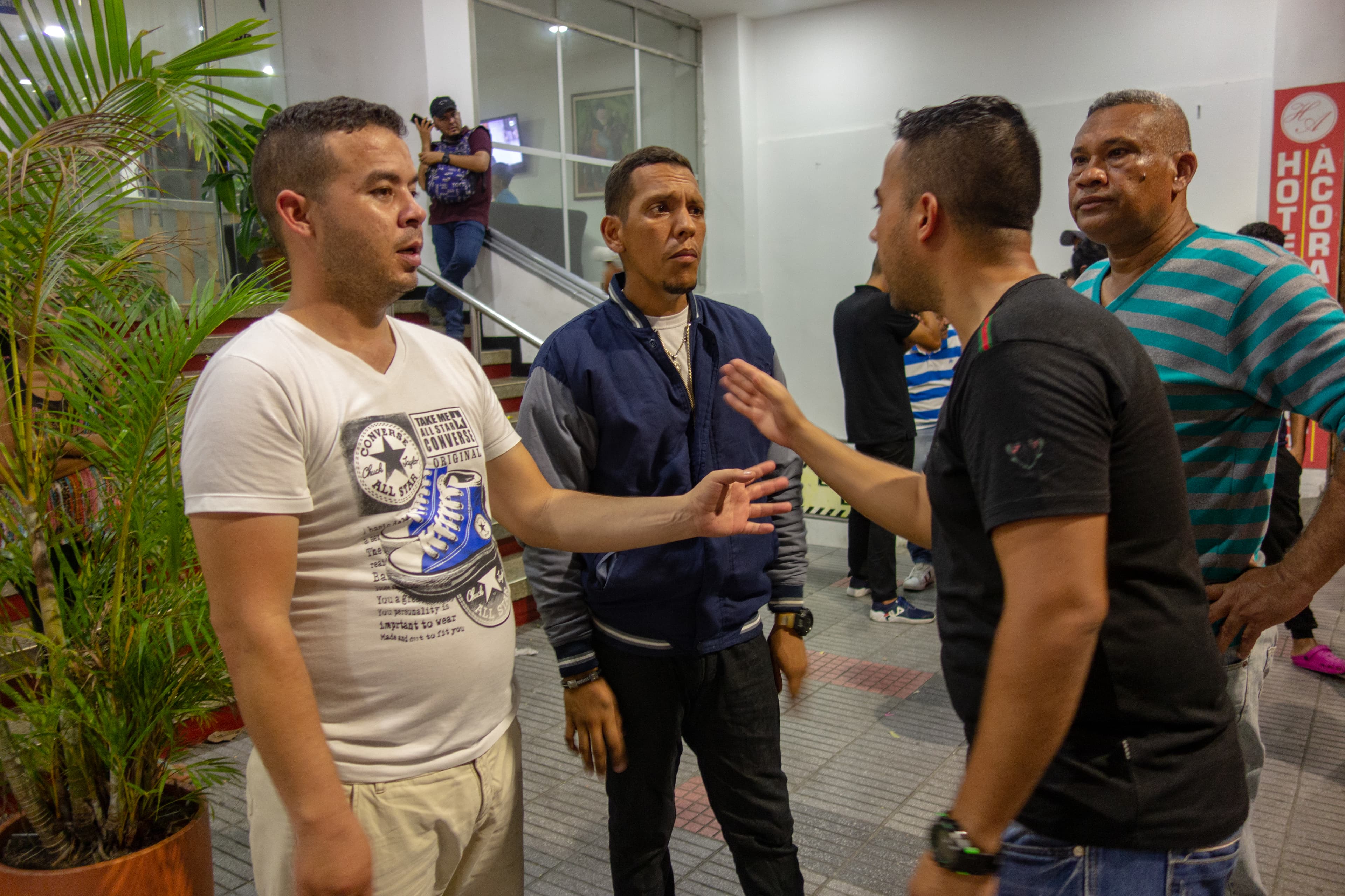 Men in a lively discussion using their hands in front of a hotel.