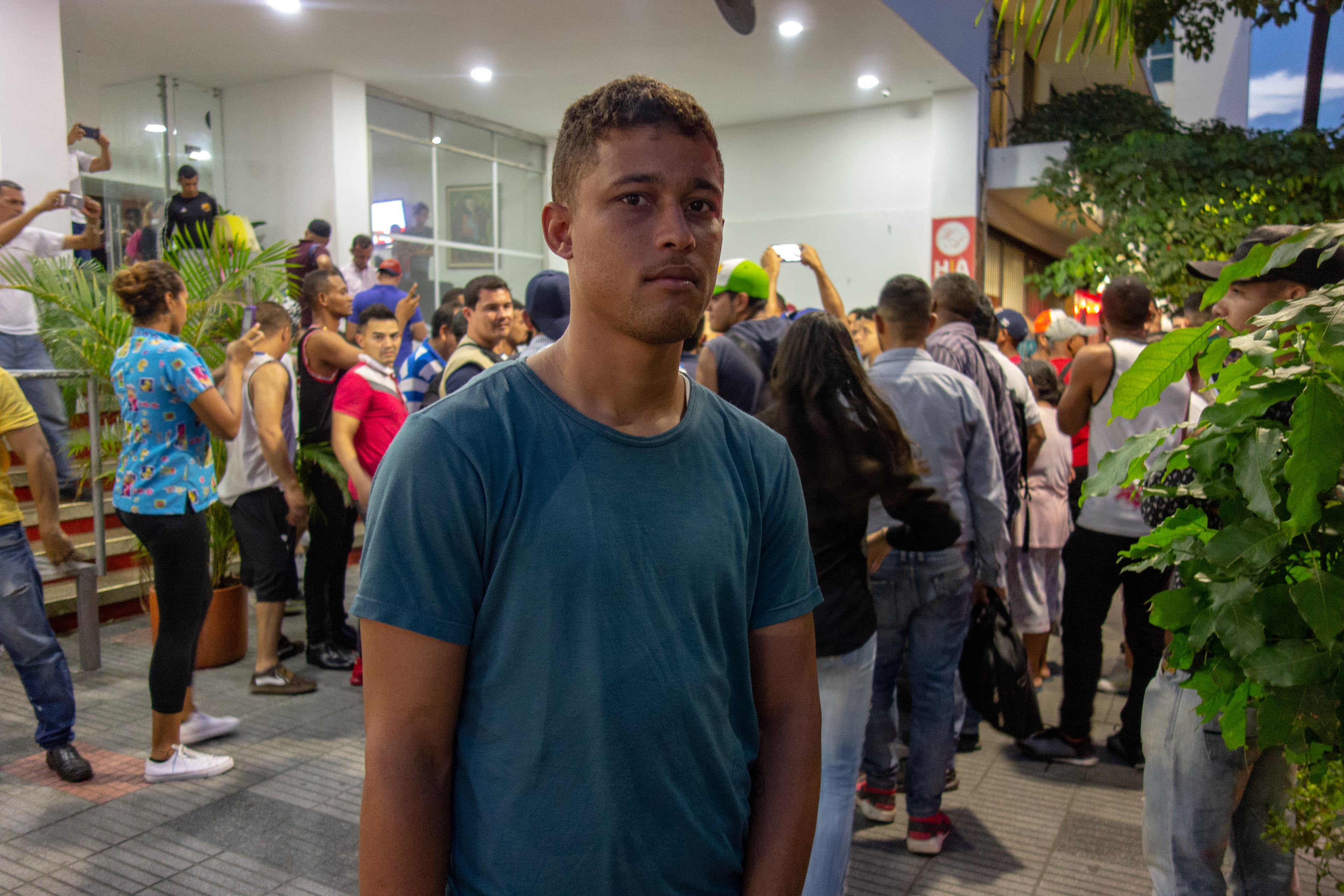 A man wears a blue shirt in front of hotel