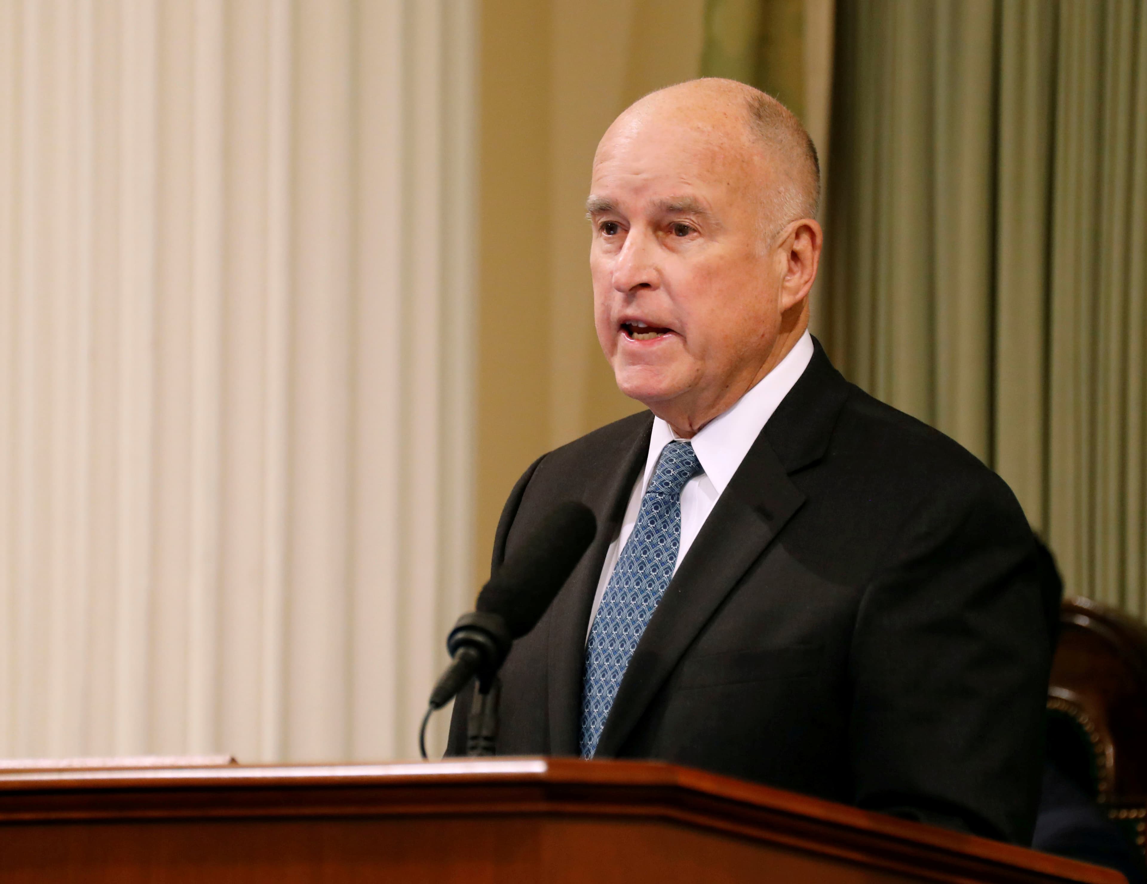 Former Governor Jerry Brown stands at a podium.