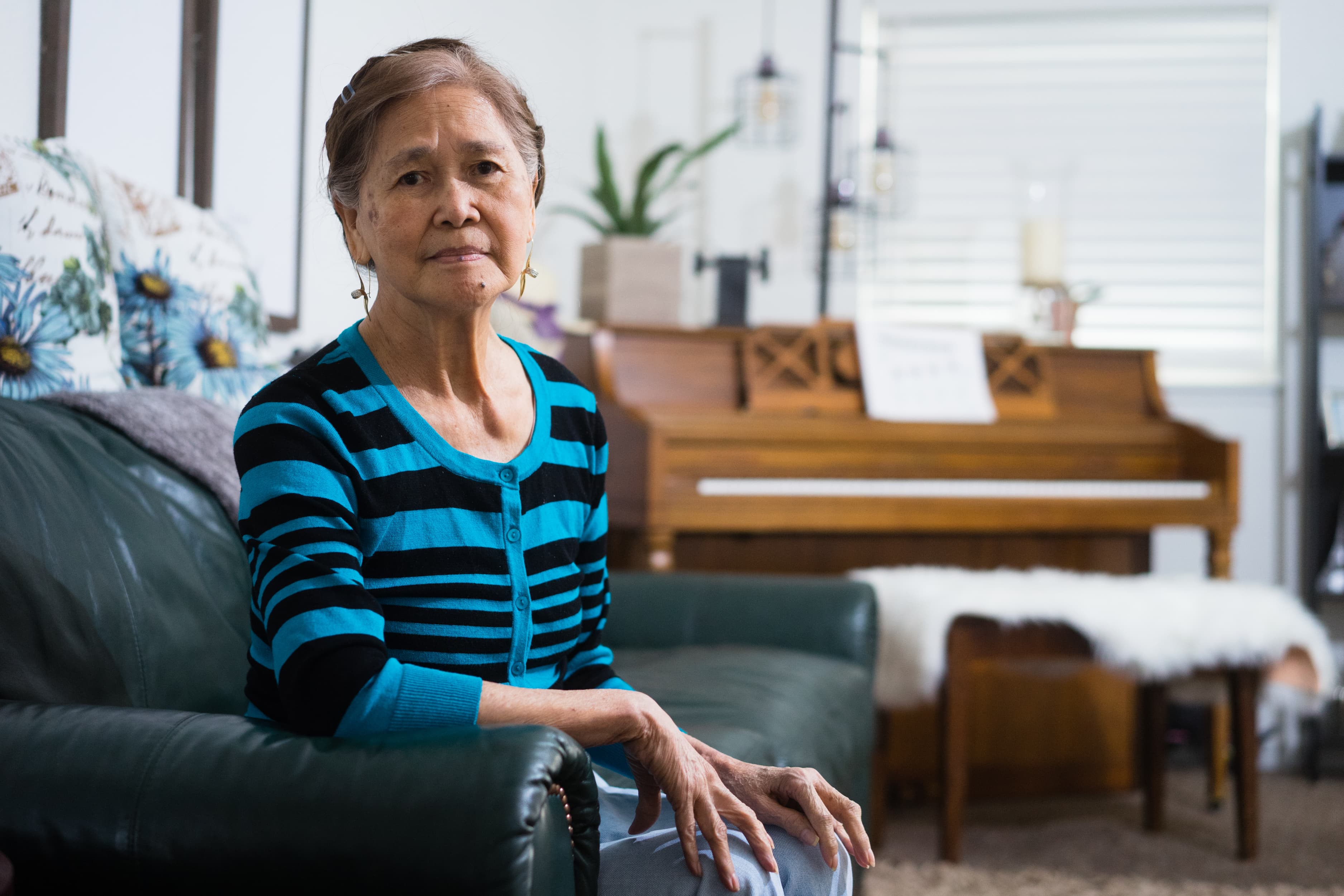 A woman sits on a couch in a home.