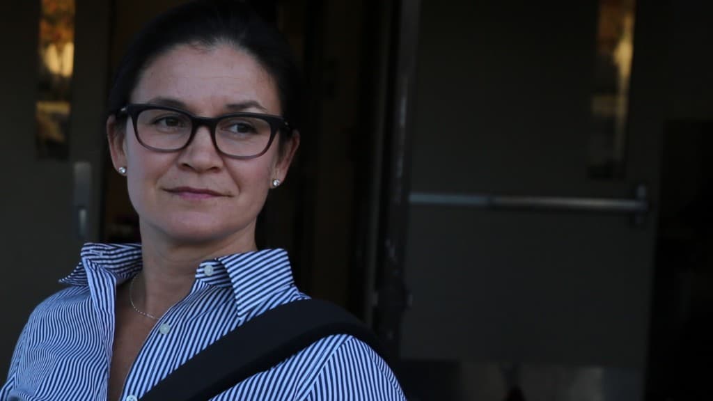 A woman wearing glasses is looking off-camera.