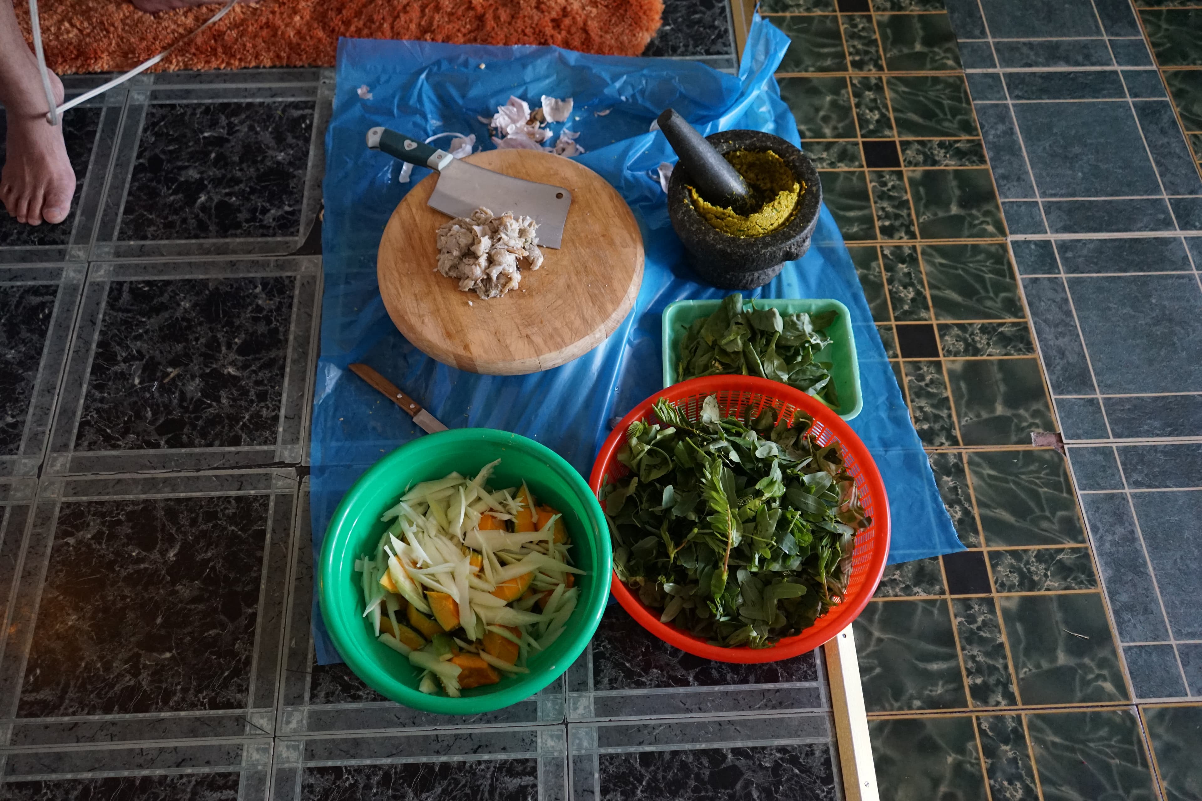 a cutting board, chopping leafy greens for a spicy Cambodian stew.