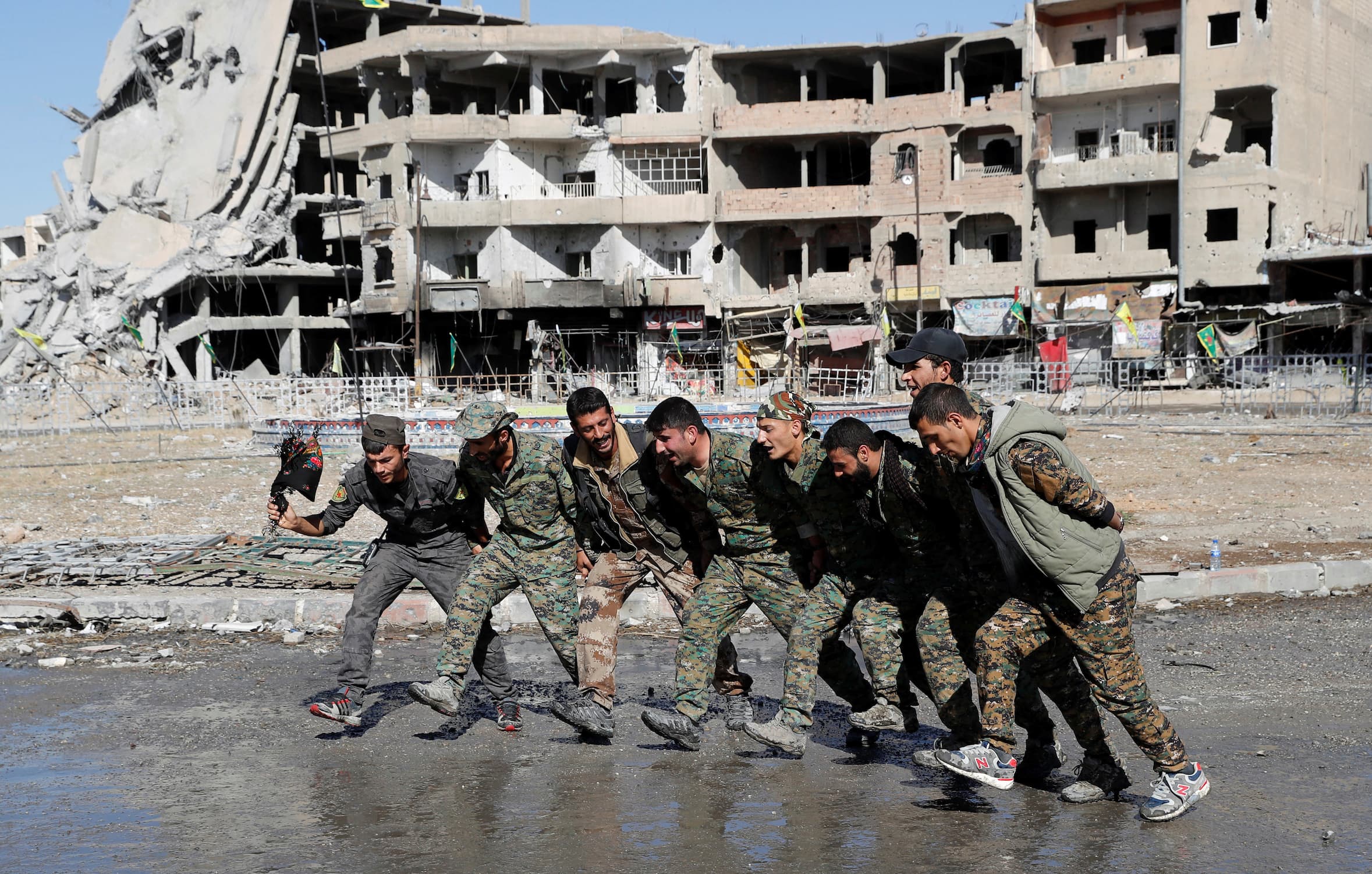 Syrian Democratic Forces fighters dance along a street in Raqqa, Syria, on Oct. 18, 2017.